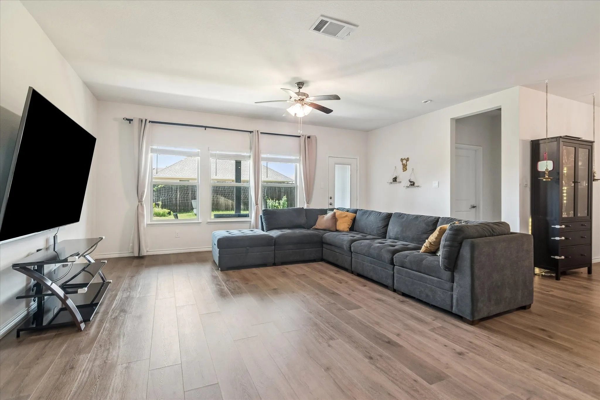 Wood-finish flooring throughout, ceiling fan with integrated lighting, recessed lighting, and multiple windows