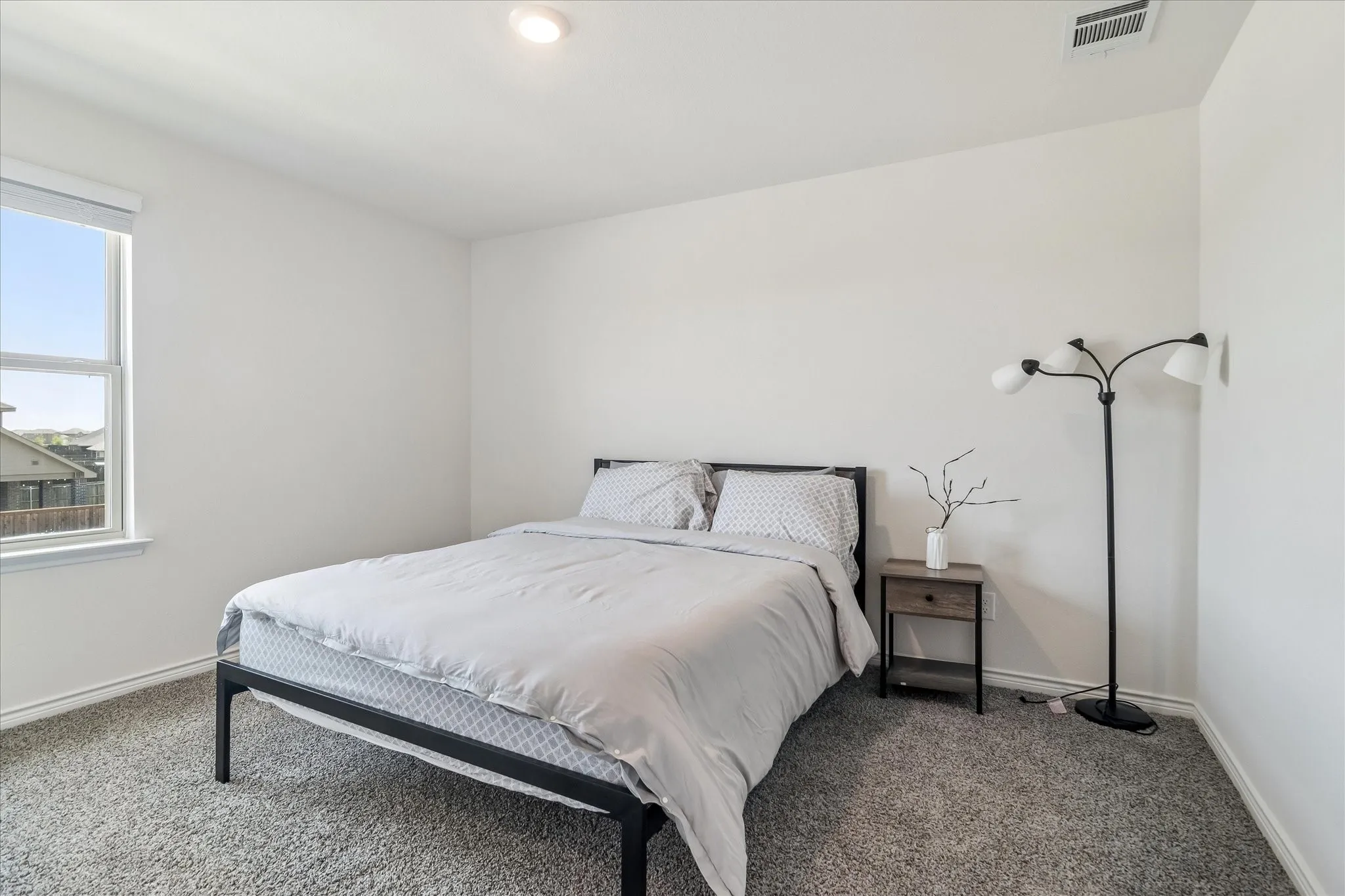 Window with white frame, textured carpet flooring, recessed ceiling lighting, and white walls