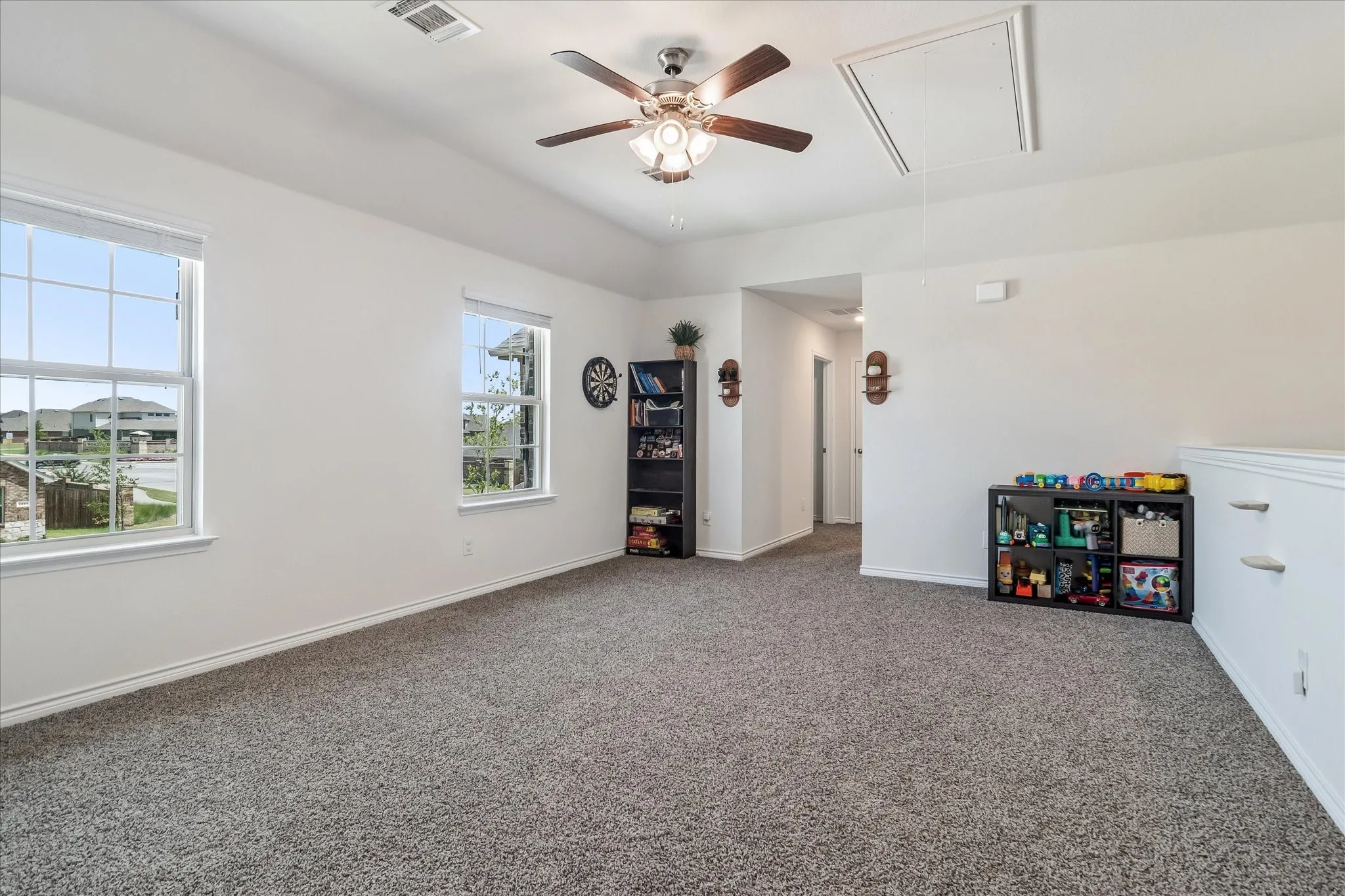 Spacious room featuring vaulted ceilings, ceiling fan, and carpet flooring