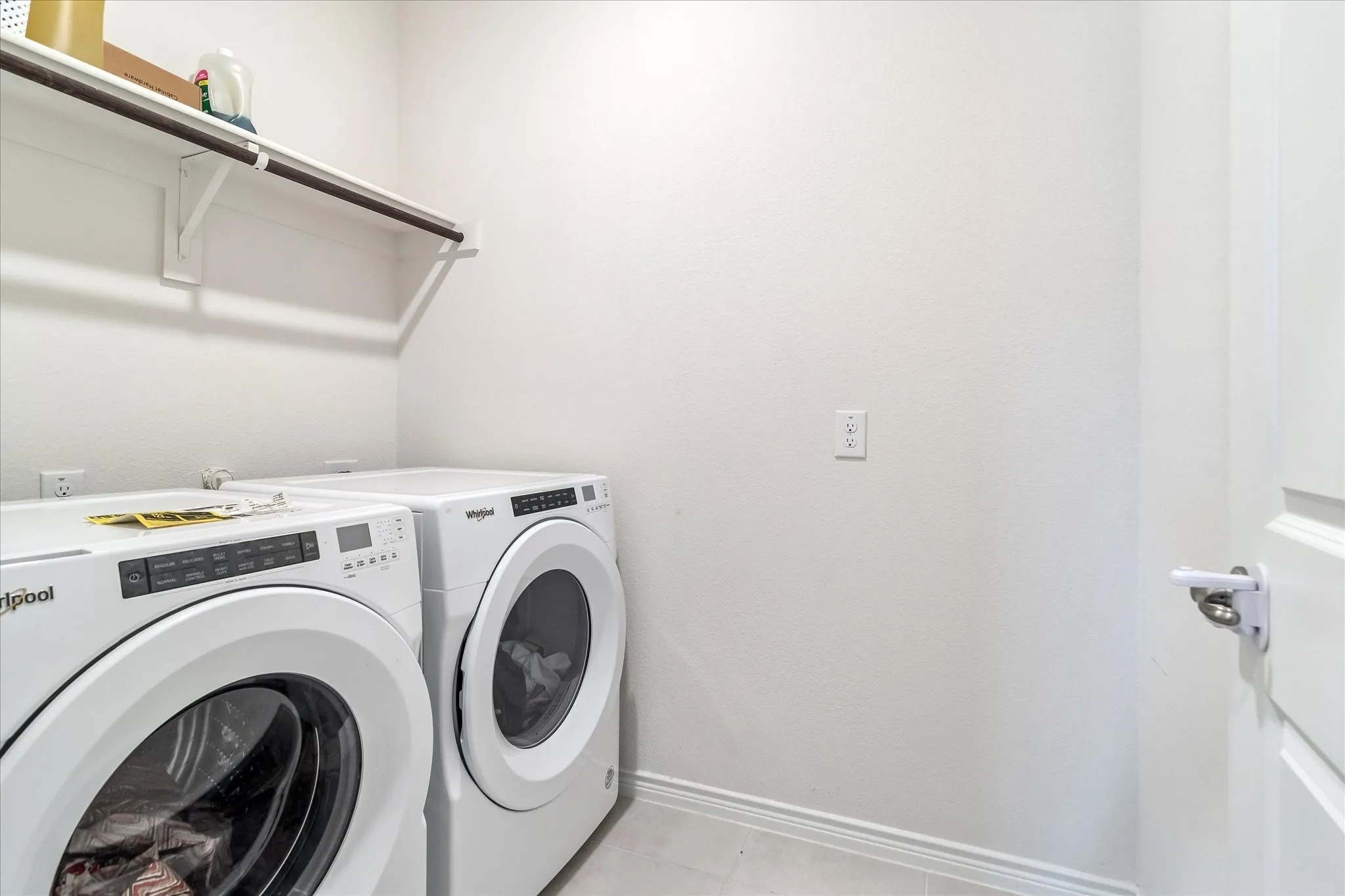 Integrated laundry area featuring a white shelf and hanging rod