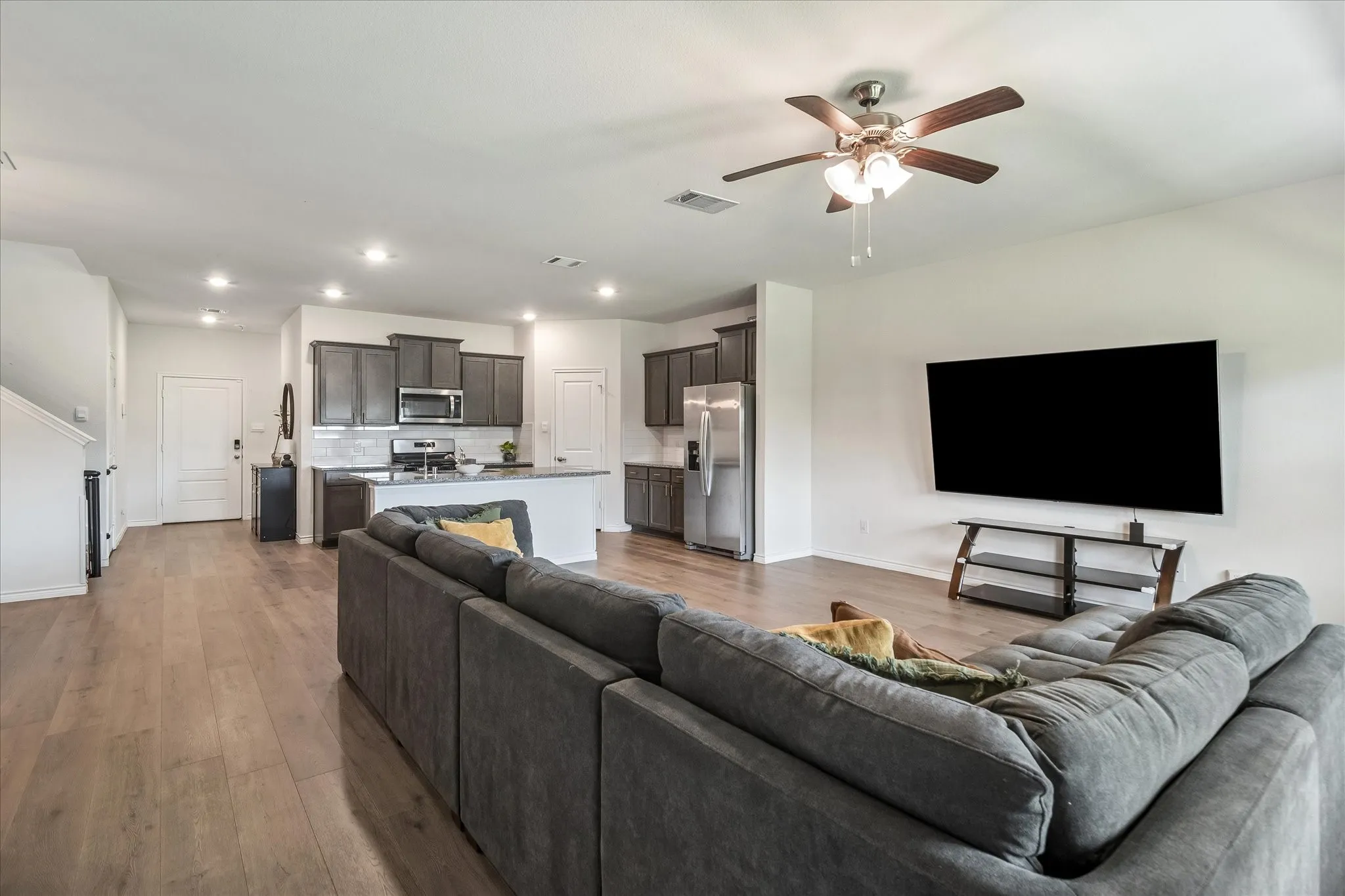 Open-concept living area with wood-finish flooring, recessed lighting, and a ceiling fan