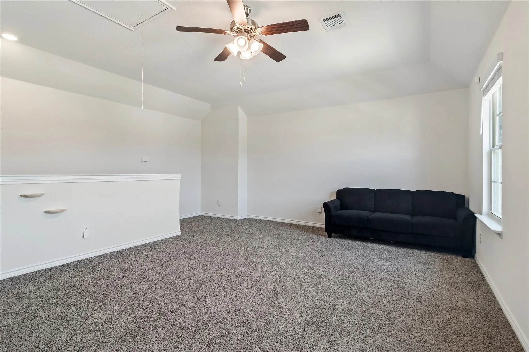 Spacious loft area featuring vaulted ceilings, a ceiling fan, and carpeted flooring