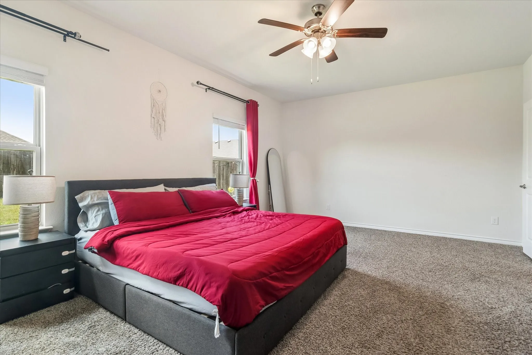 Vaulted ceiling bedroom with carpet flooring, two windows, and a ceiling fan with integrated lighting