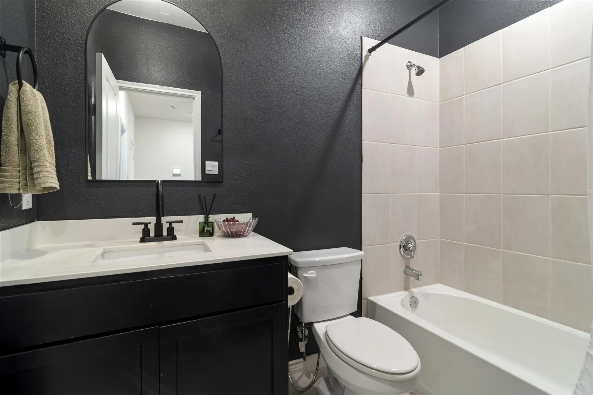 Black vanity with white countertop, rectangular under-mount sink, and black wall-mounted faucet