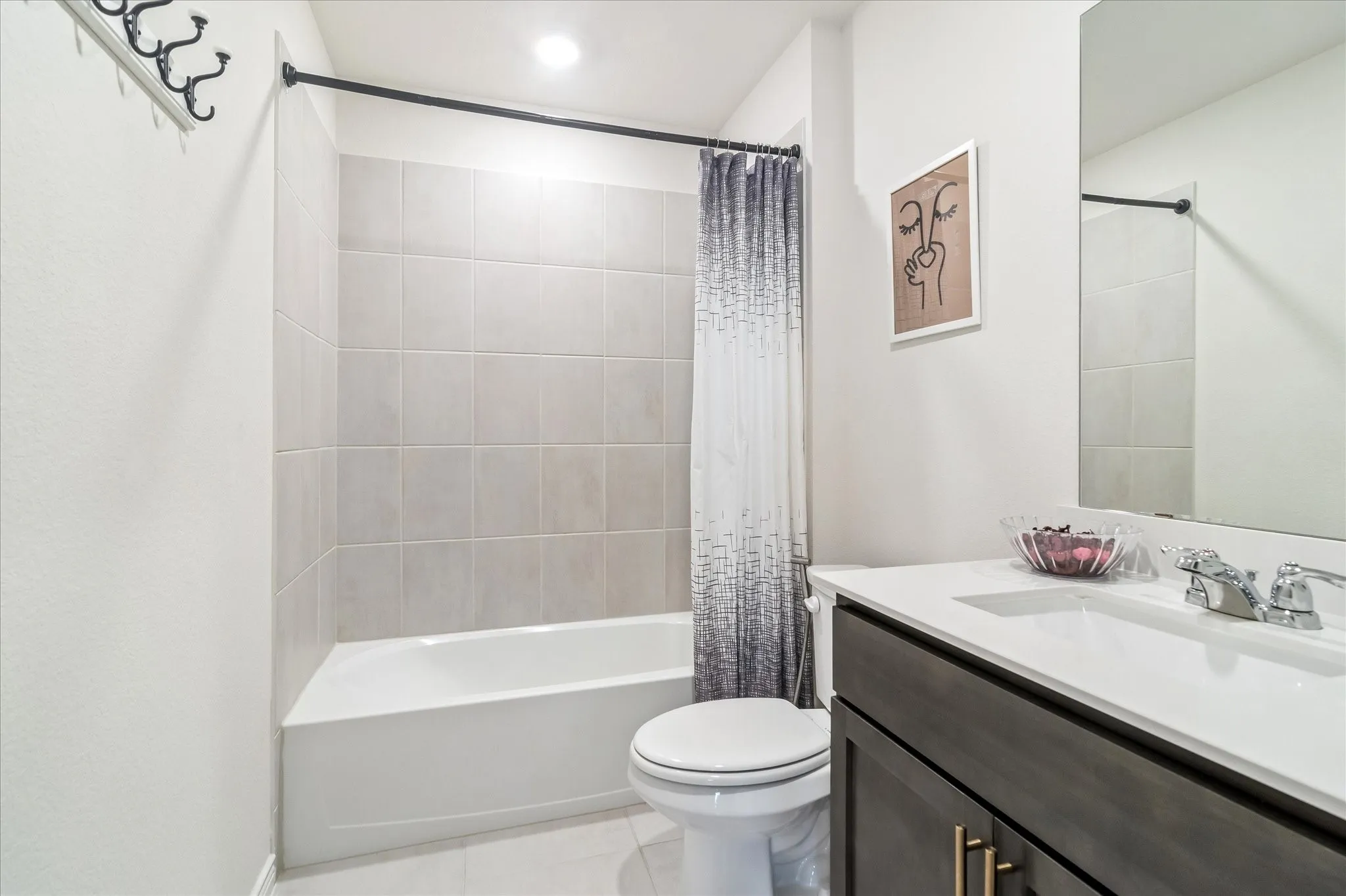 Bathroom featuring a white tub, light-toned tiled shower surround, recessed ceiling lighting, a dark wood-finish vanity with a white countertop, and an integrated sink with a chrome faucet