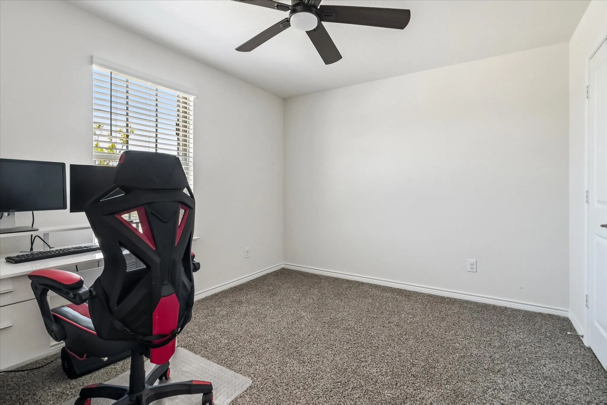 Neutral color palette featuring textured carpeting and a ceiling fan with integrated lighting