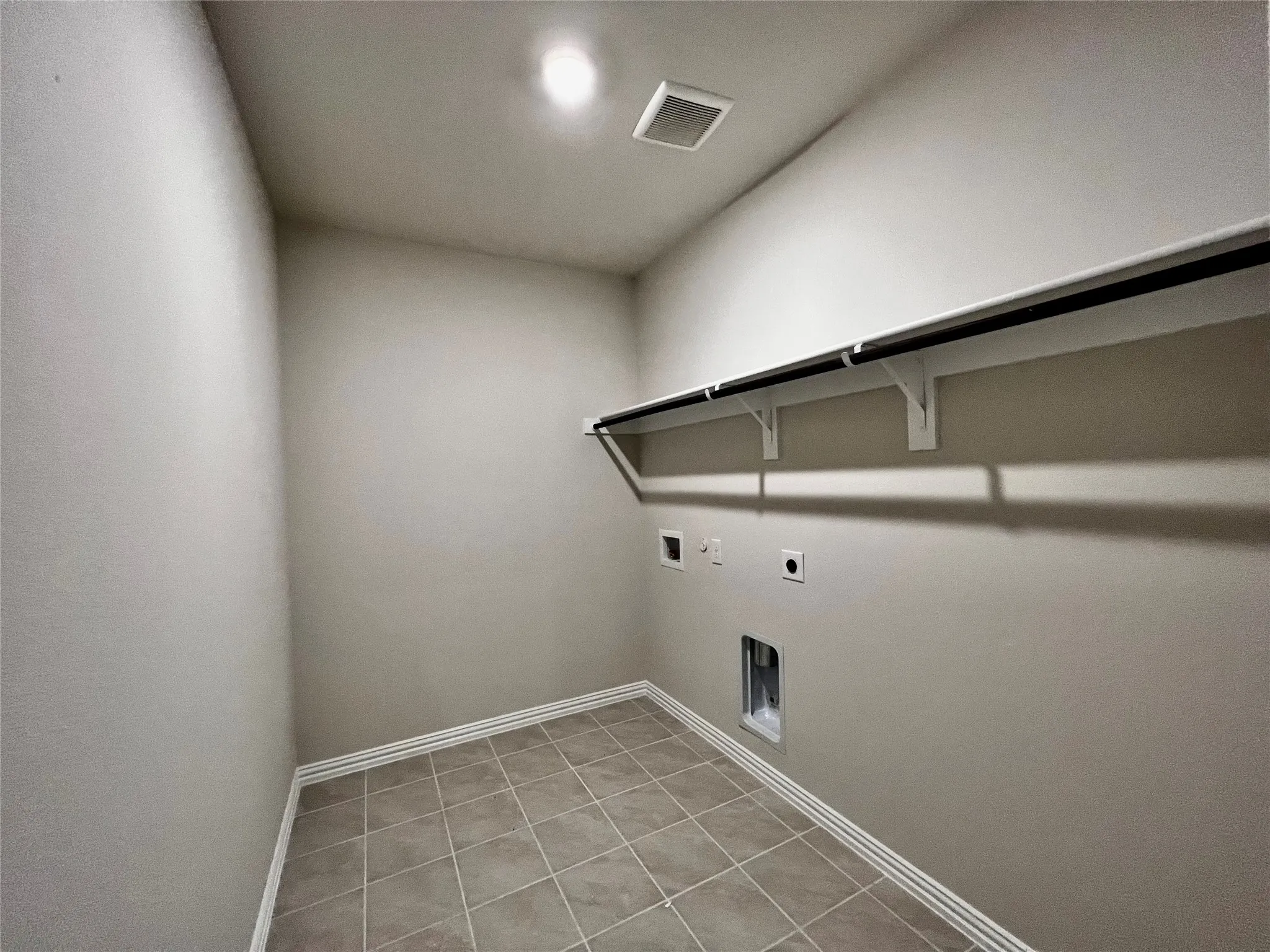 Tiled flooring, overhead lighting, wall-mounted shelving, and appliance hookups