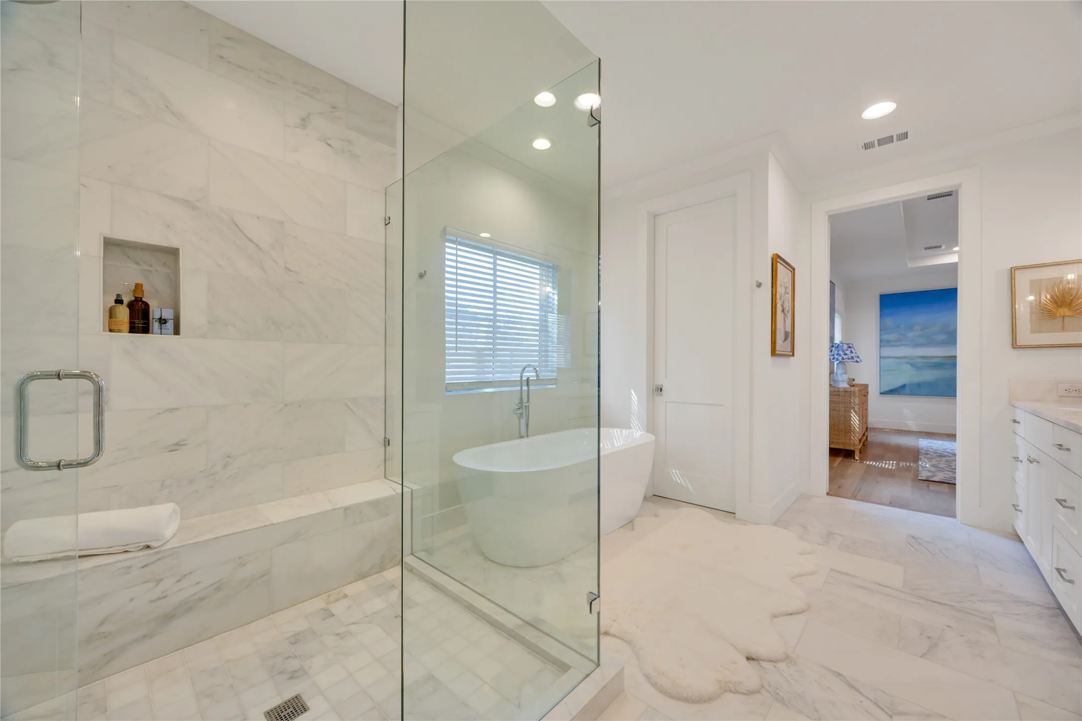 Another view of the primary bathroom showing the soaking tub, door to water closet, and open double doors to the bedroom.