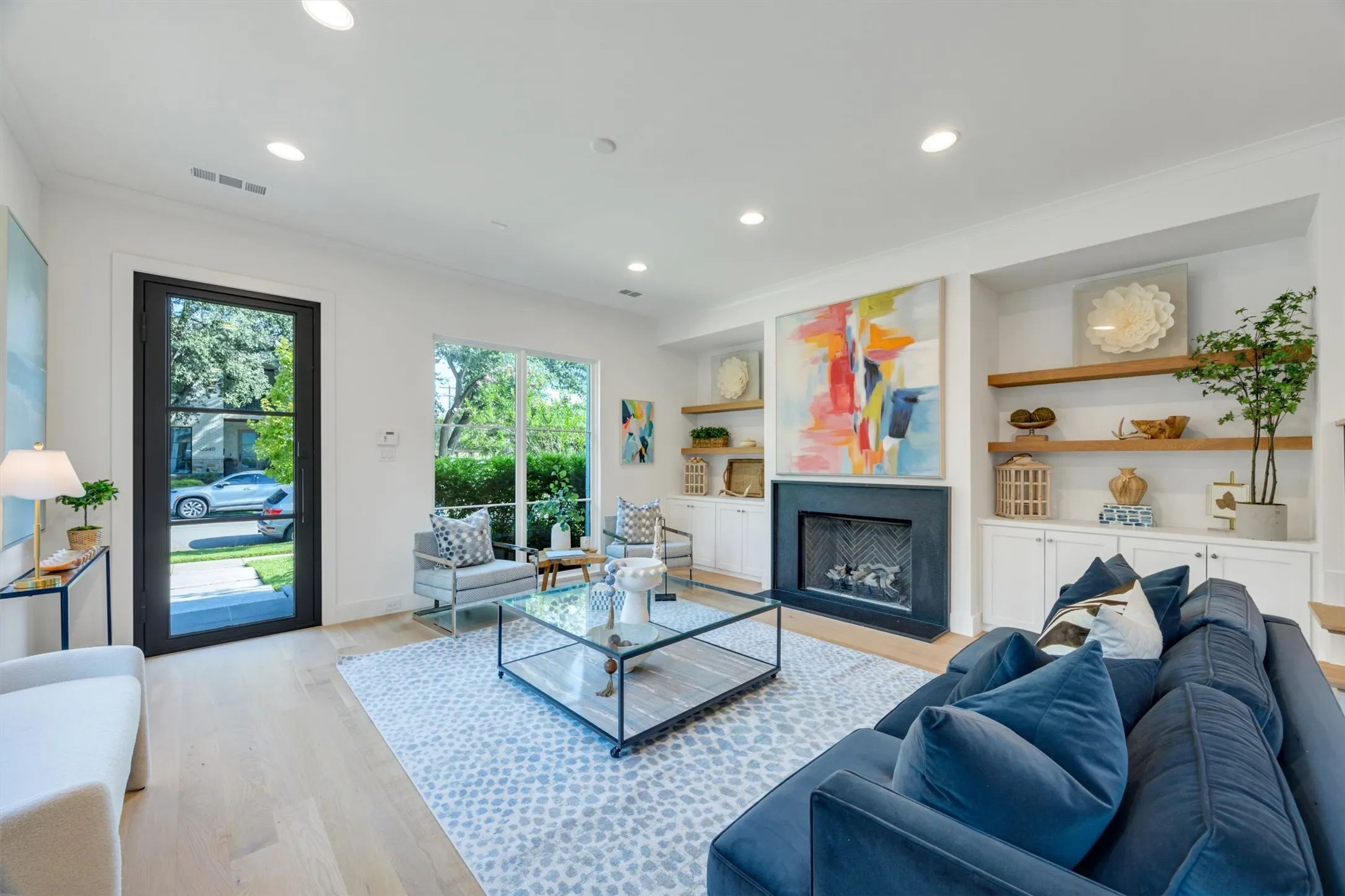 The main living area has great seating space,  features a fireplace with real stone surround, large windows for natural light, and built in shelves with storage cabinets underneath.