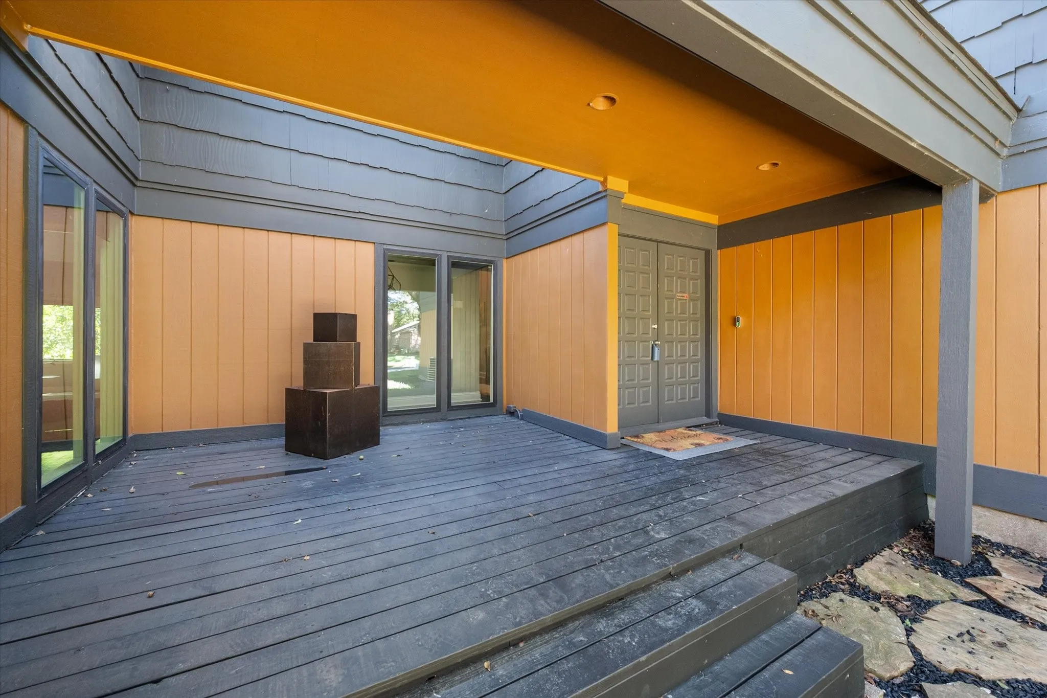 Recessed entry featuring a wood deck, dual entry doors, multiple windows, and exterior wall paneling