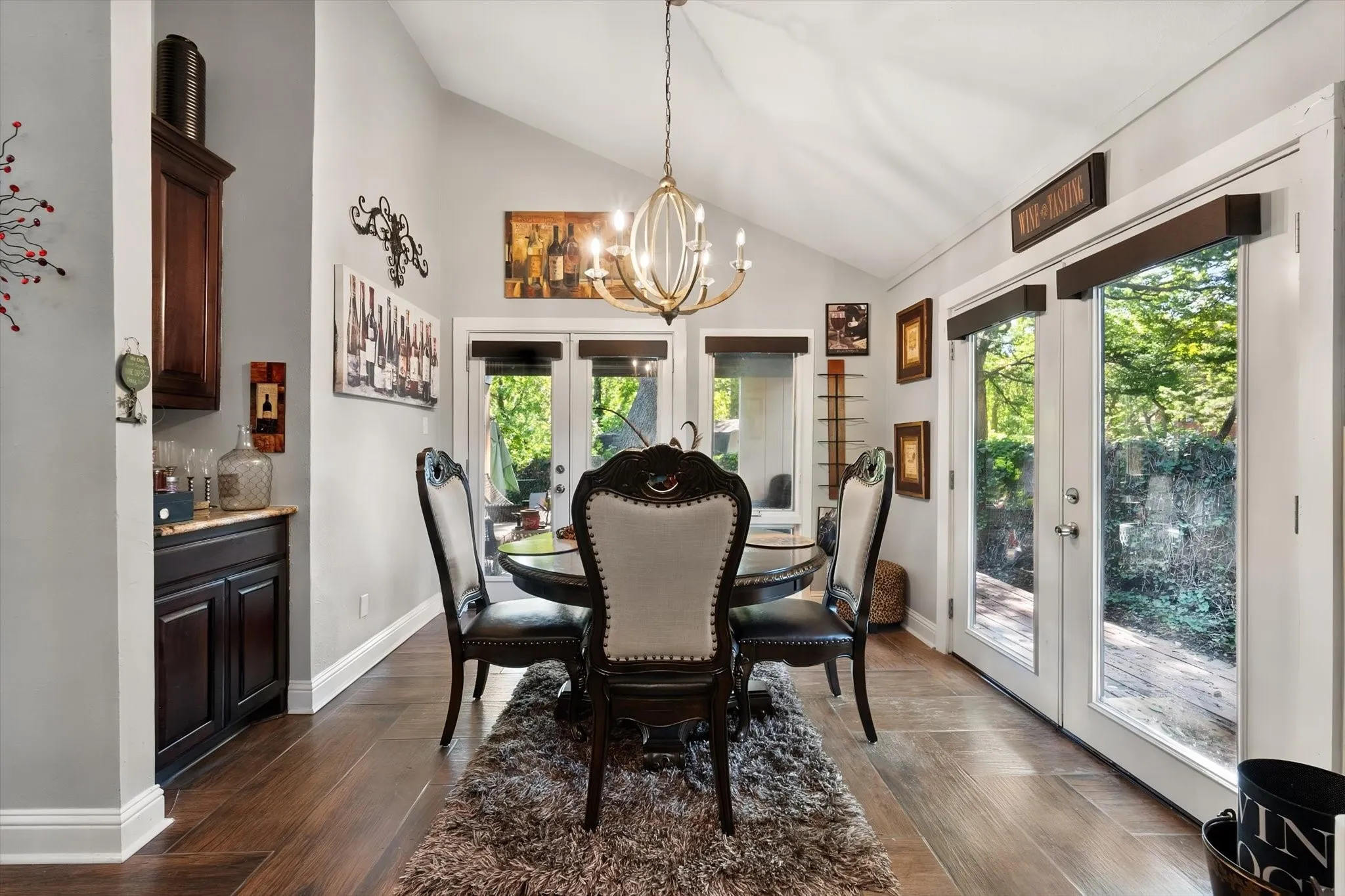 Vaulted ceiling with an ornate chandelier, wood-finish flooring, built-in cabinetry with a stone countertop, and glass-paneled doors