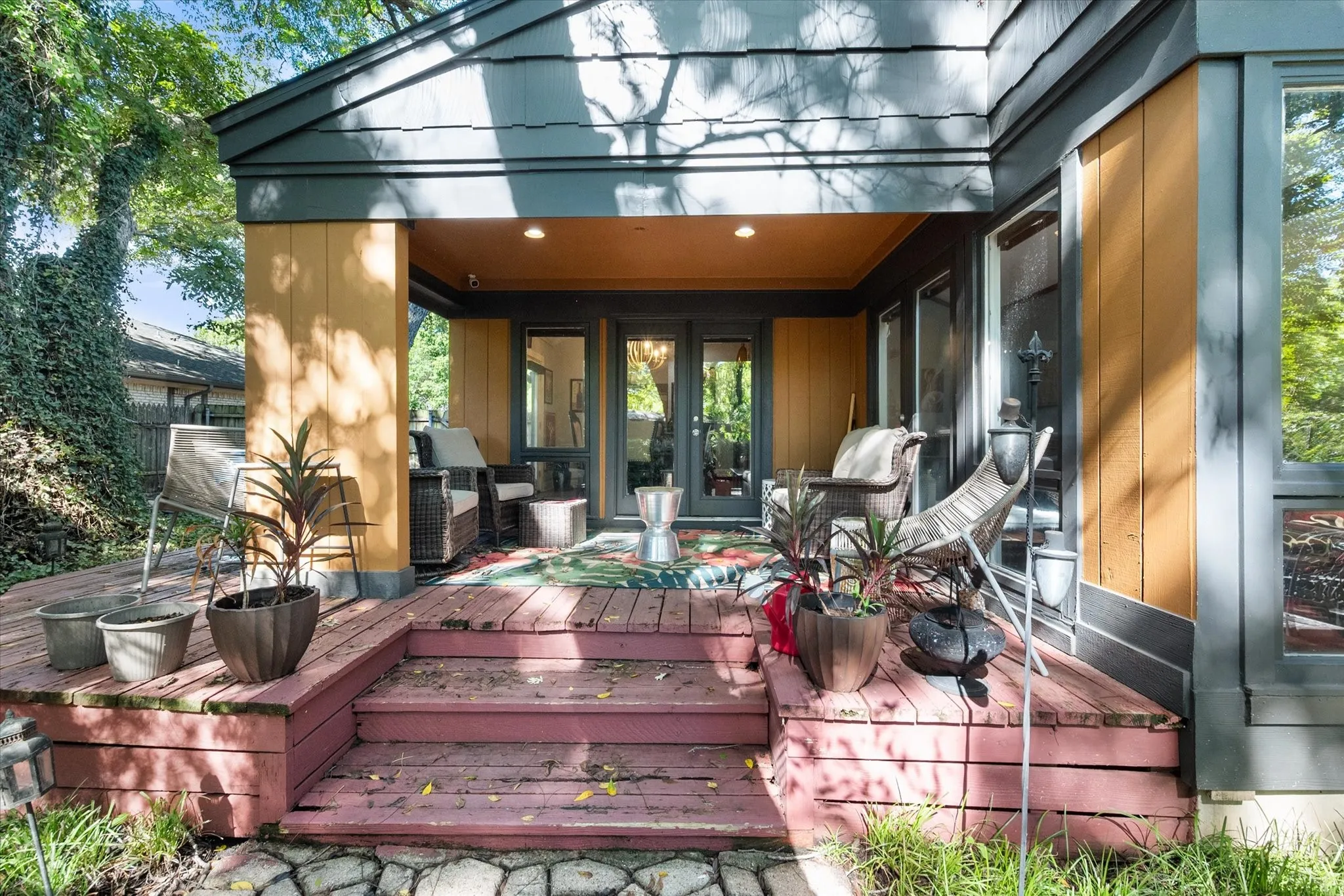 Multi-level wood deck with steps, covered patio with recessed lighting, double glass doors, and large picture windows