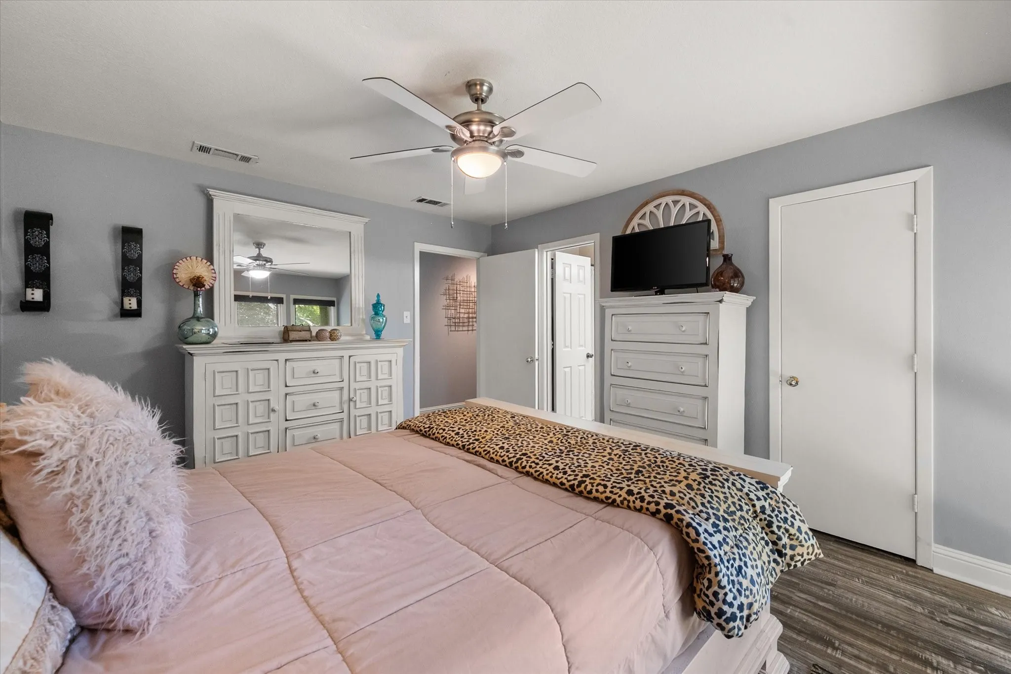 Spacious room with wood-finish flooring, light gray walls, and a ceiling fan with integrated lighting