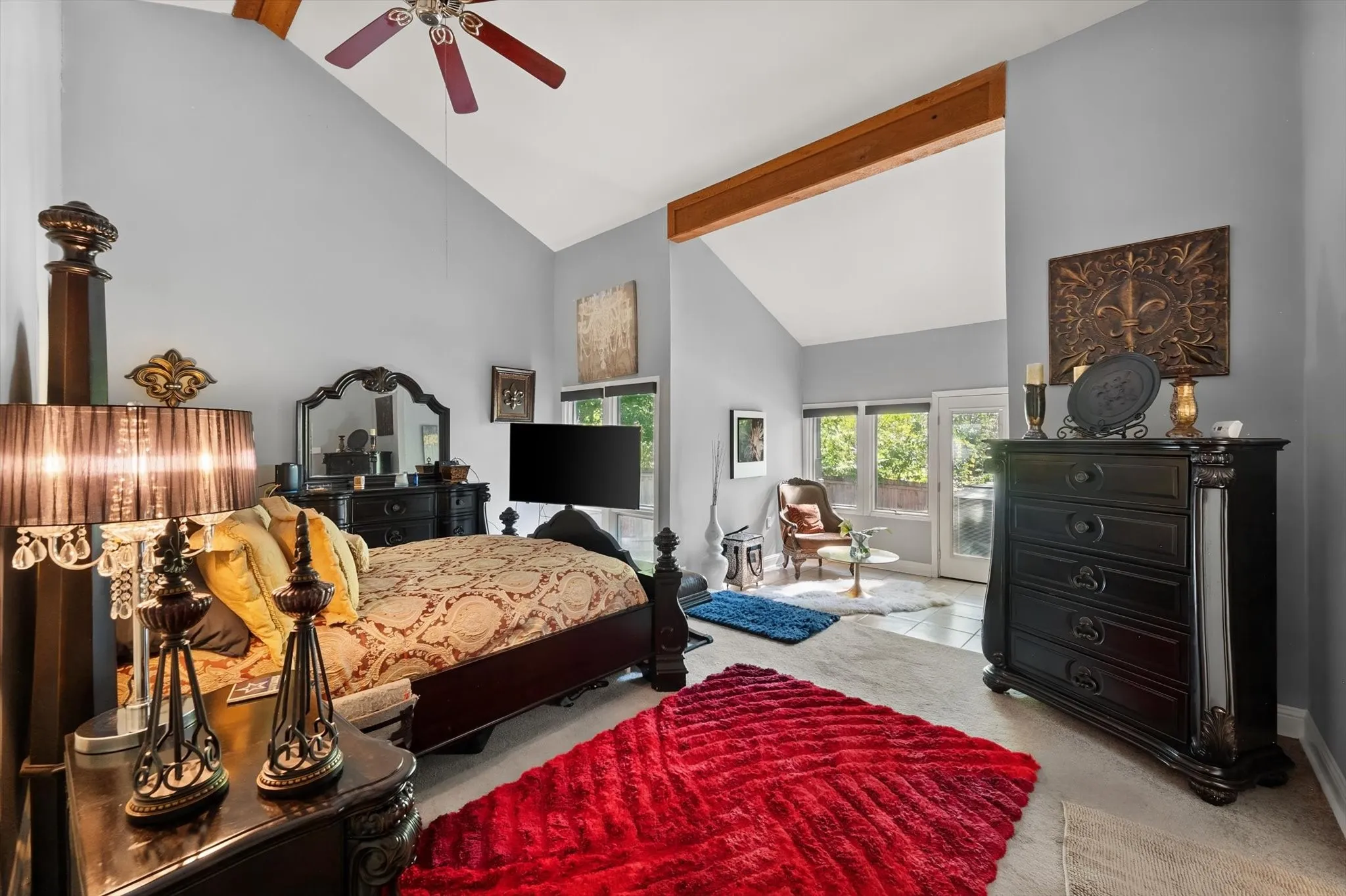 Vaulted ceiling with exposed wood beams, ceiling fan, tile flooring, and double patio doors