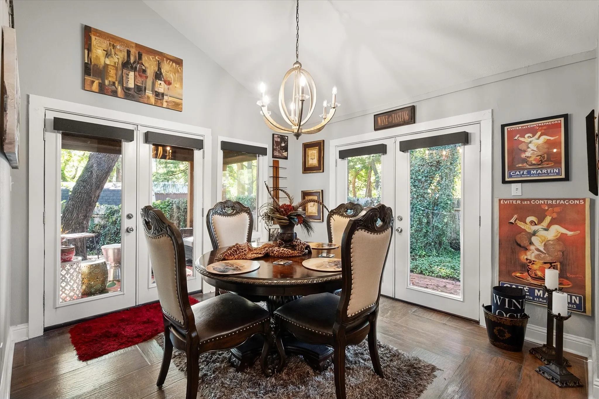 Vaulted ceiling with a chandelier, wood-finish flooring, and multiple glass-paned doors
