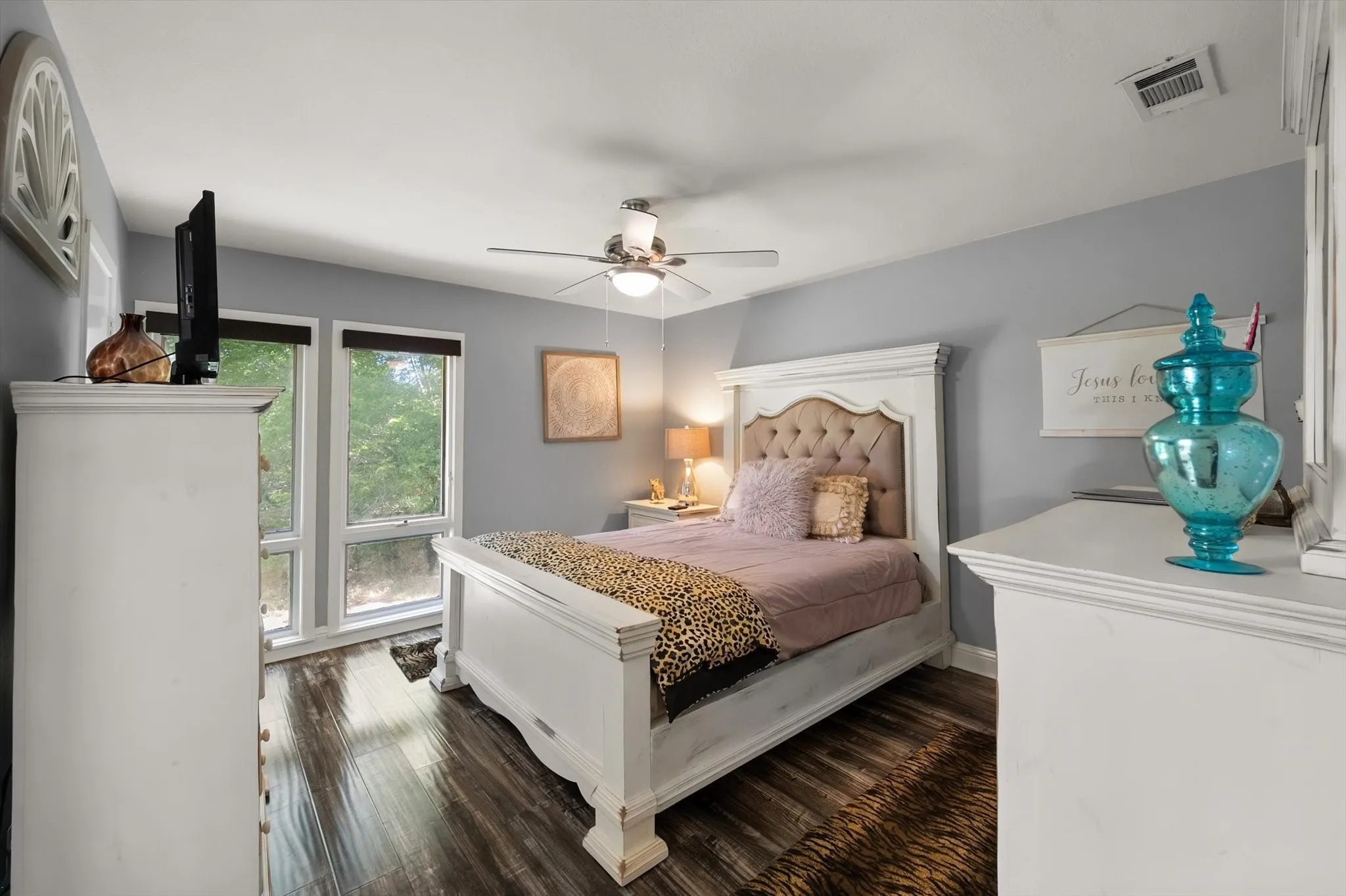 Wood-finish flooring, multiple windows, ceiling fan, and built-in dresser