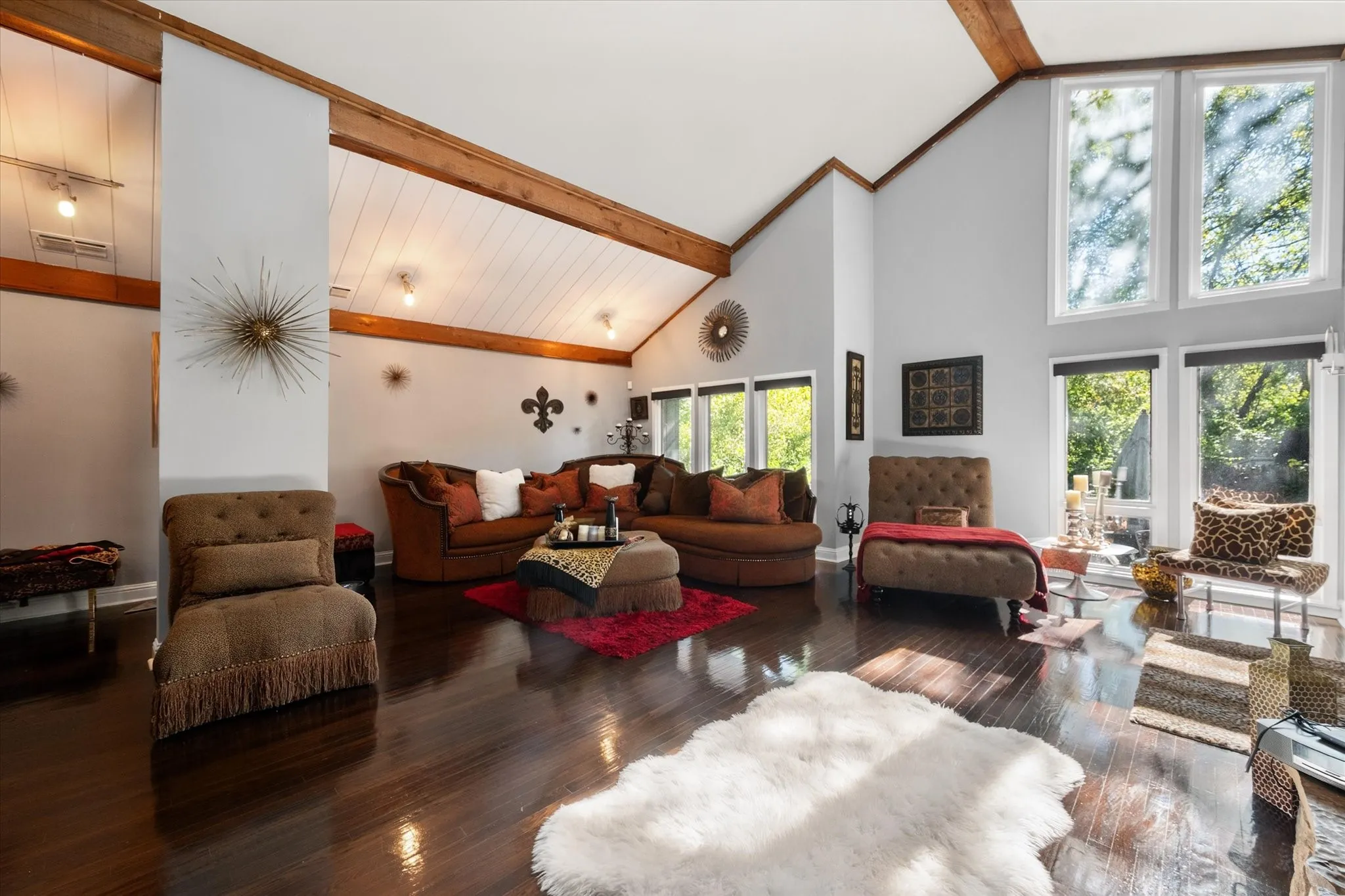 Vaulted ceiling with exposed wood beams, wood-finish flooring, and expansive windows
