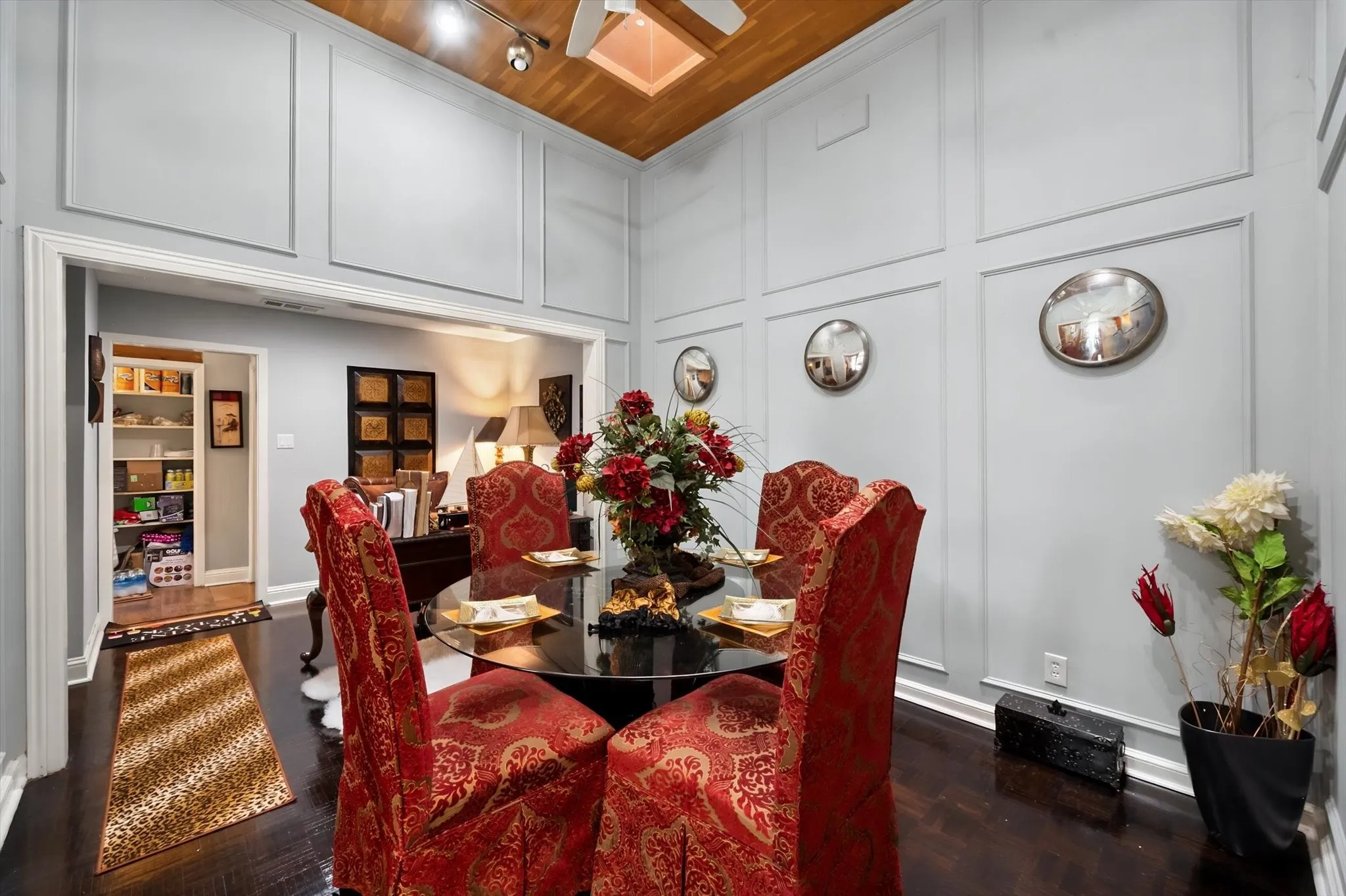 Board and batten wall detailing, dark wood-finish flooring, vaulted ceiling with wood-paneled accent, track lighting, and a wide cased opening
