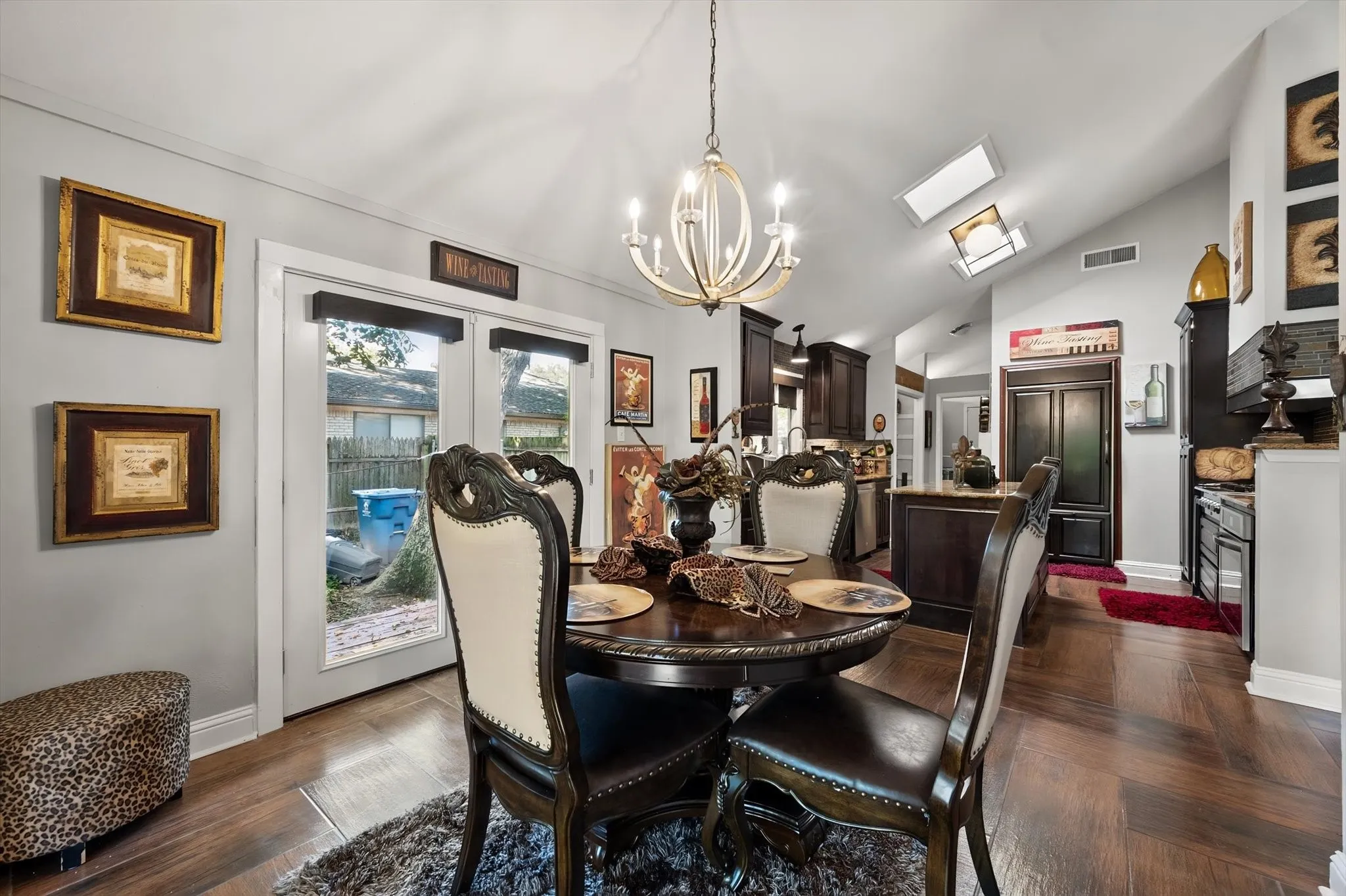 Vaulted ceiling with skylights, wood-finish flooring, French doors, recessed lighting, and a contemporary chandelier