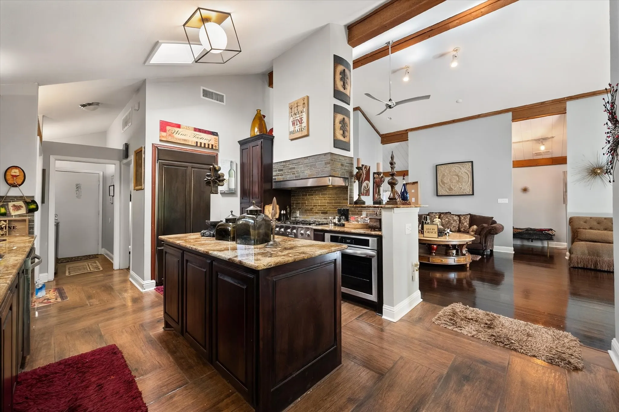 Kitchen featuring a central island, wood-finish flooring, vaulted ceiling with exposed beams, and stainless steel appliances