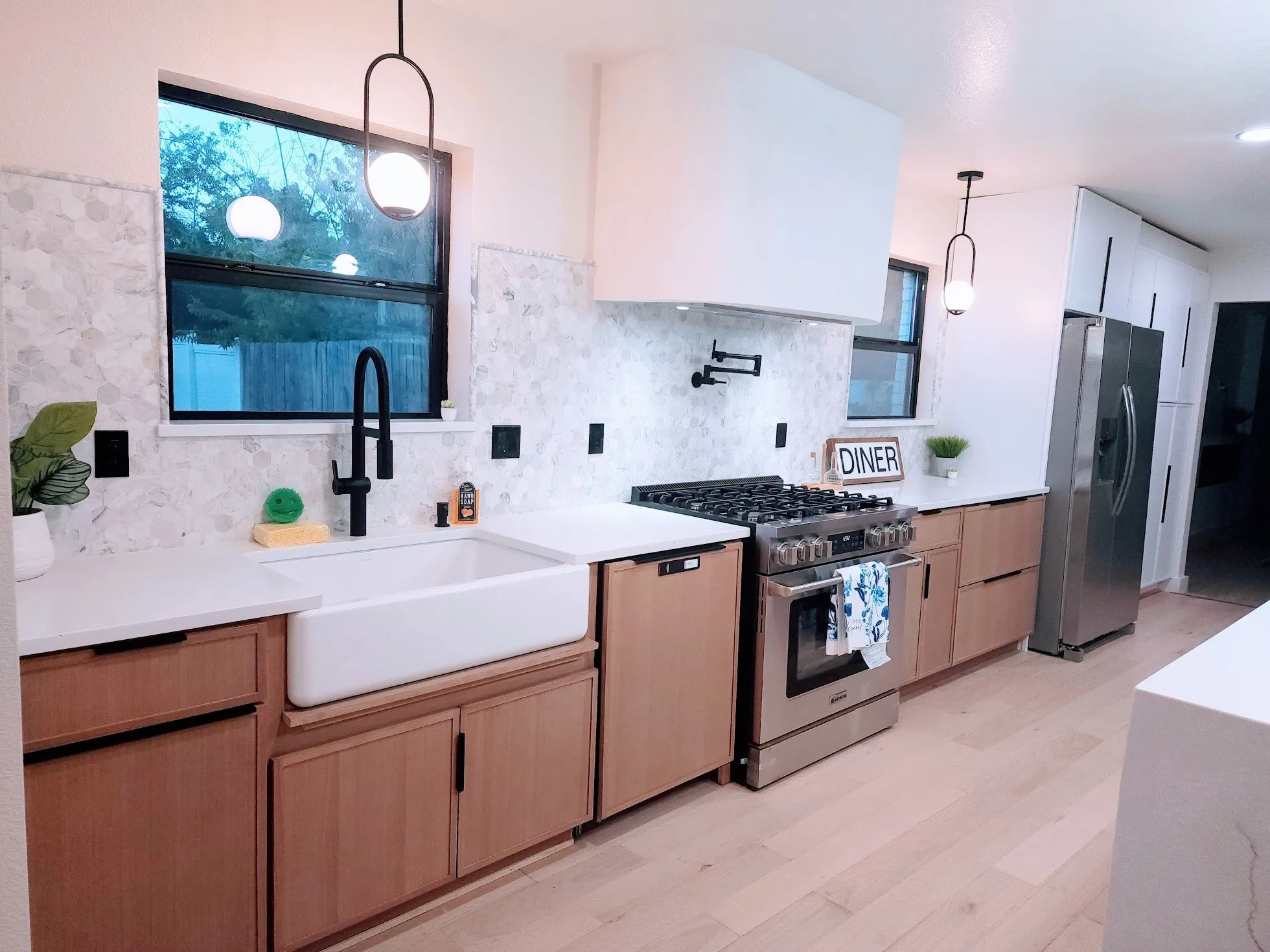 Contemporary kitchen featuring light wood-finish cabinetry, a large farmhouse sink, stainless steel appliances, and quartz countertops