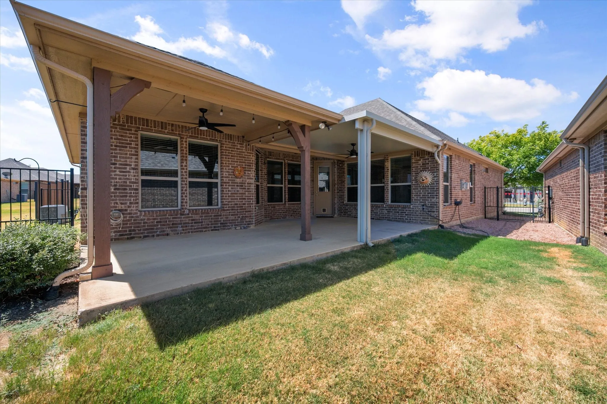 Extended covered back patio creates an inviting outdoor living space, complete with ceiling fans and ample room for relaxing or entertaining. The fenced backyard offers a private setting for gatherings, pets, and outdoor enjoyment.