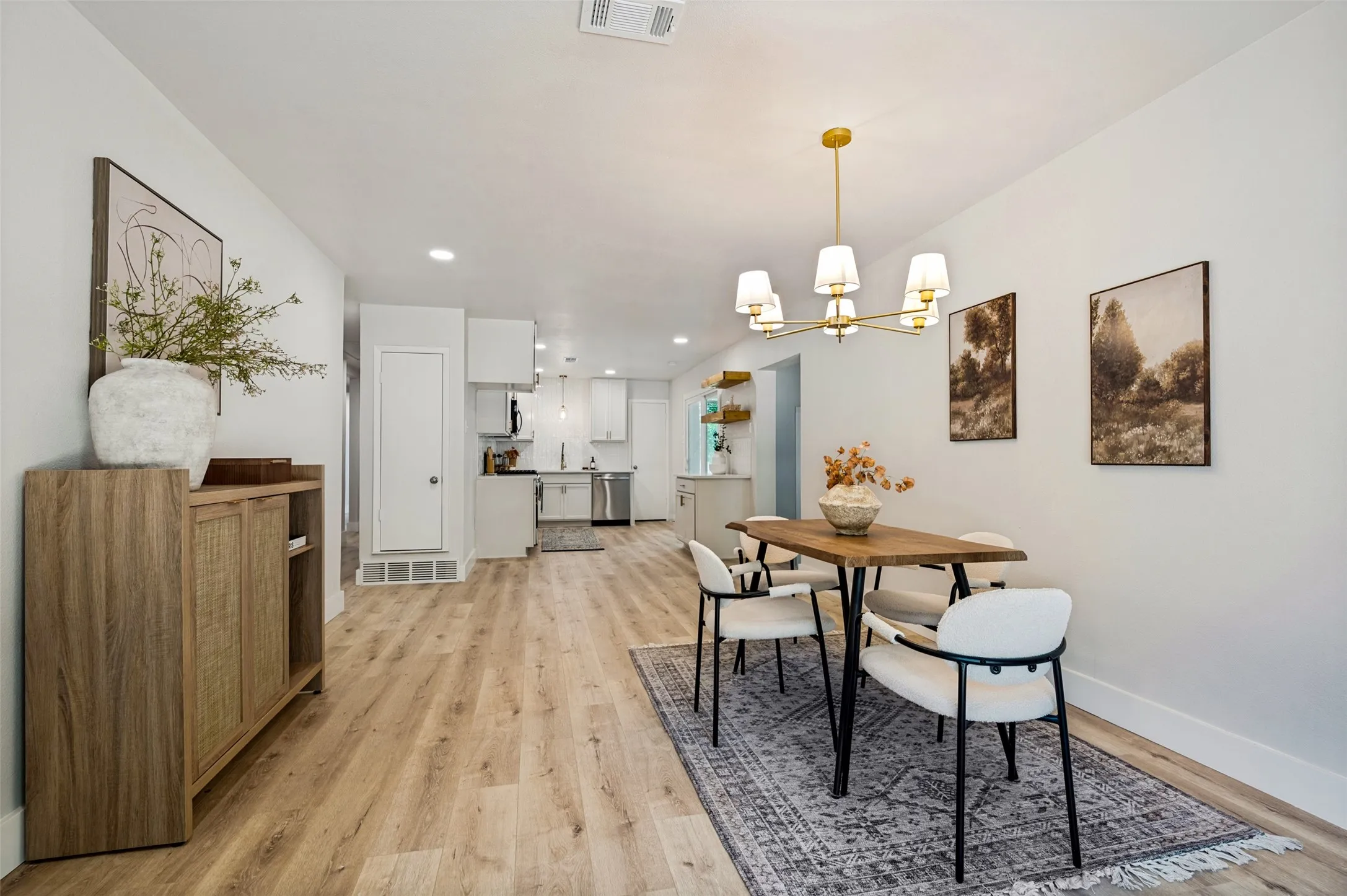 Open-concept living area featuring wood-finish flooring, recessed lighting, and a gold-tone chandelier