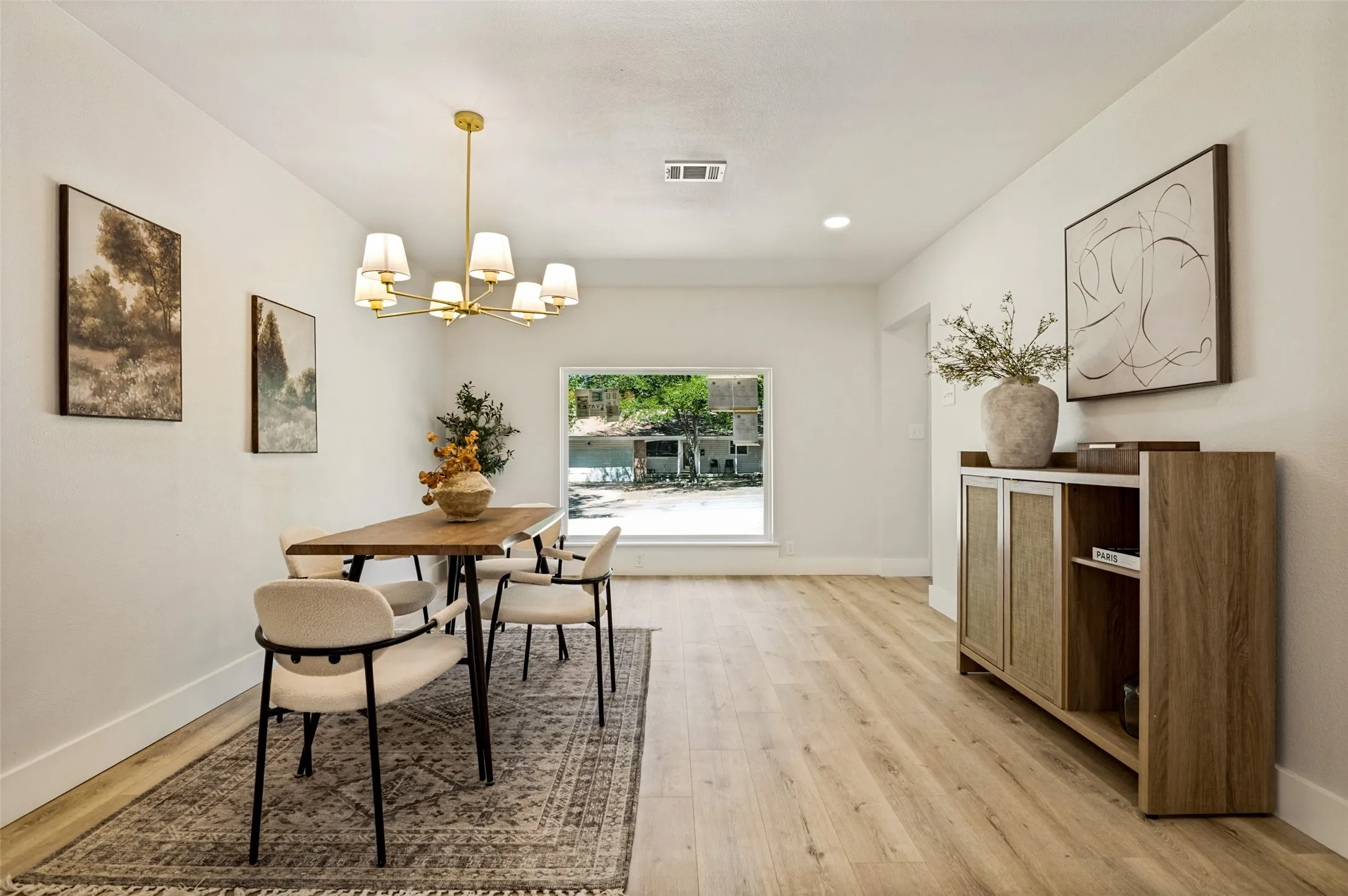 Expansive room with wood-finish flooring, a contemporary chandelier, and a large​​‌​​​​‌​​‌‌​‌‌​​​‌‌​‌​‌​‌​​​‌​​ window