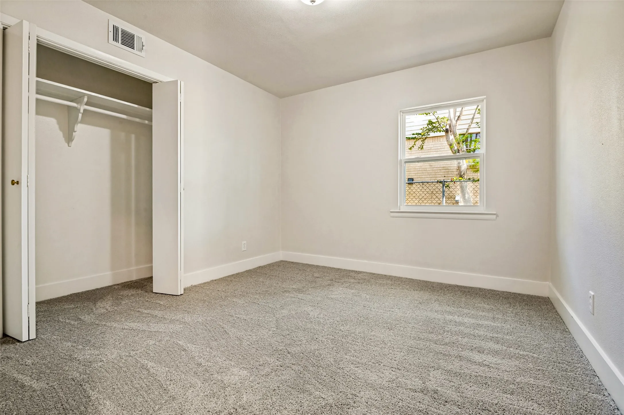 Neutral wall finishes, textured carpet flooring, built-in closet with shelving, and a single pane window