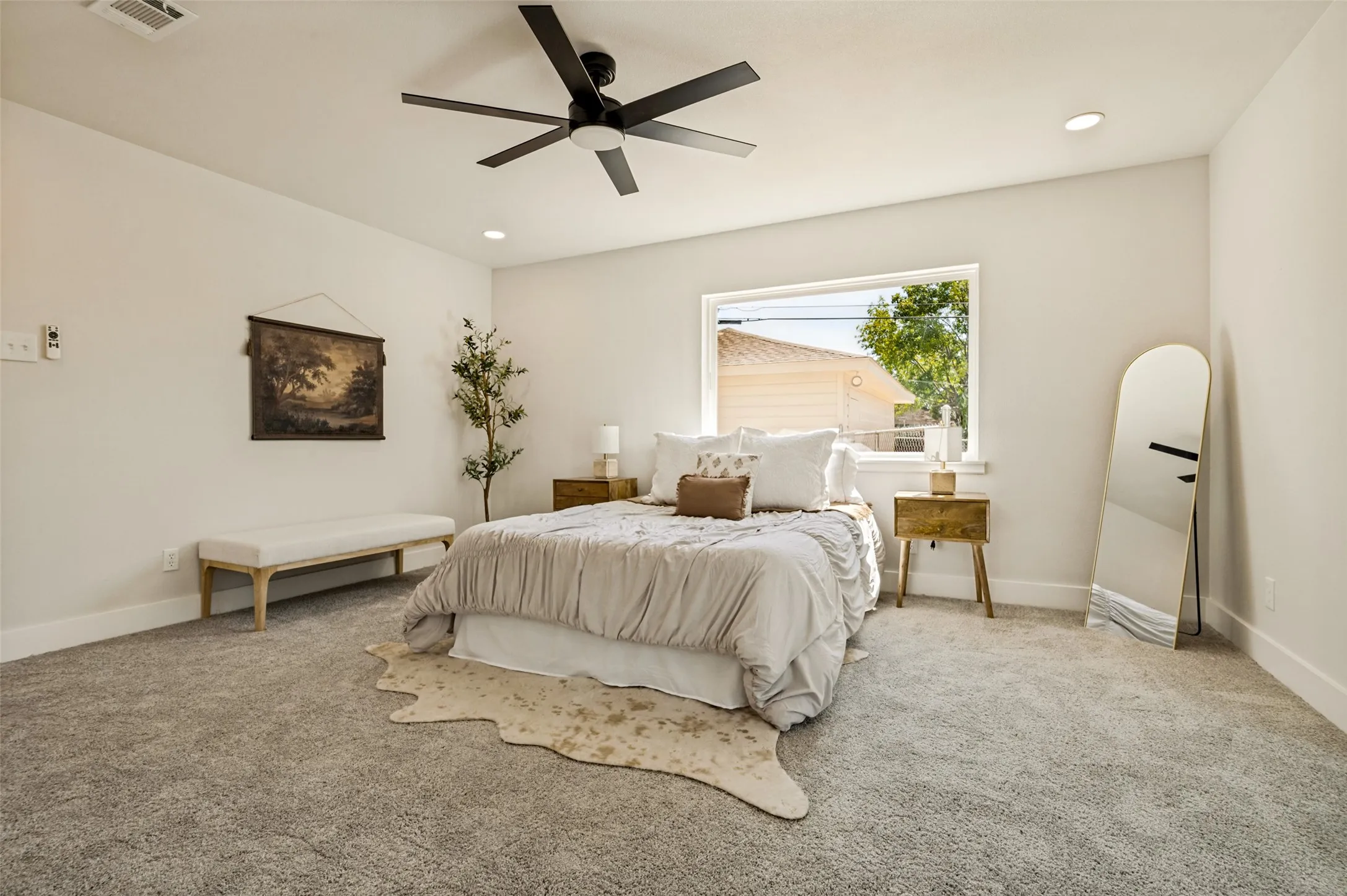 Recessed lighting, ceiling fan with integrated light, large window, and light-colored carpeting