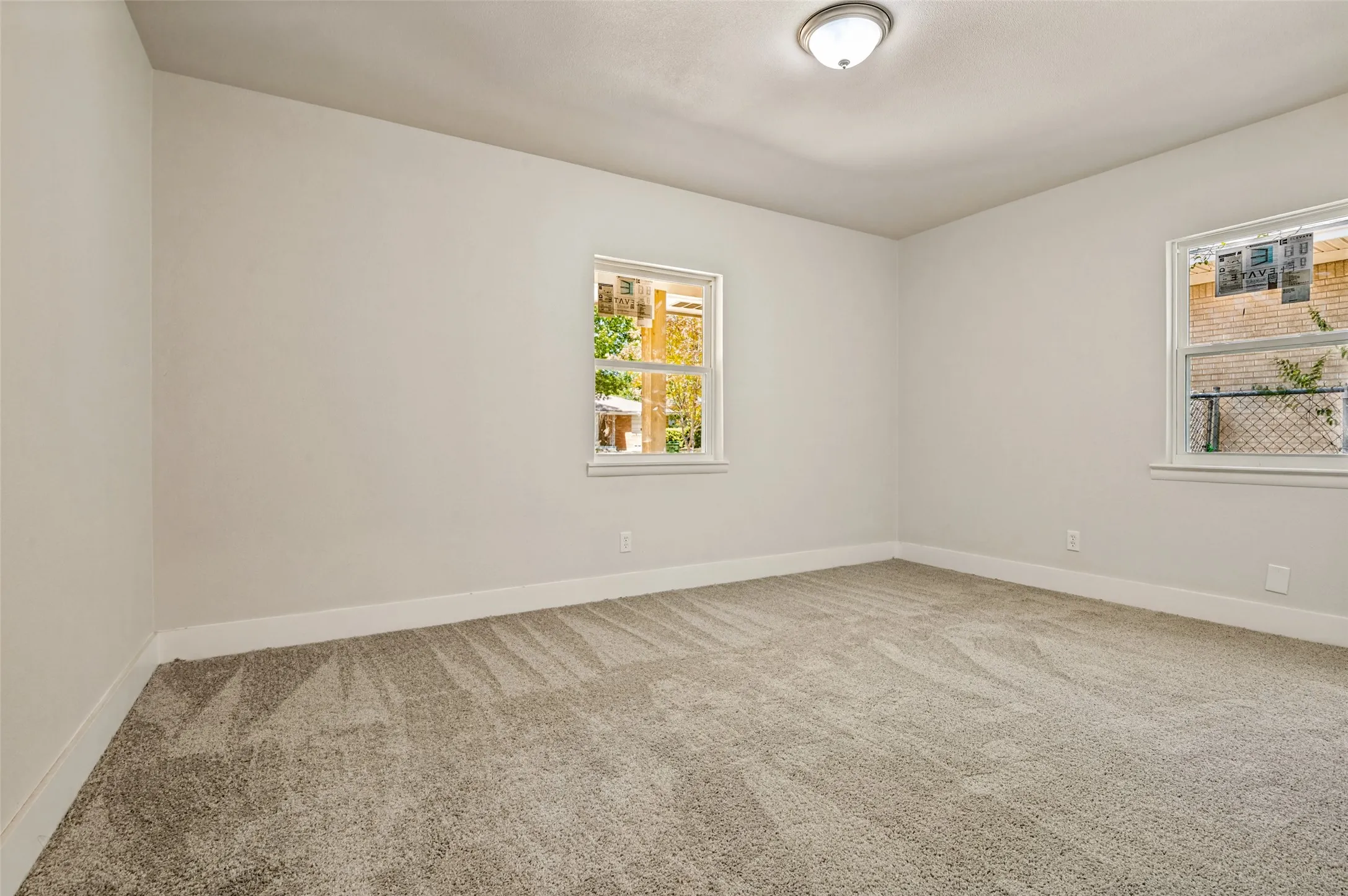 Neutral wall finishes with two windows, carpeted flooring, and a ceiling-mounted light fixture