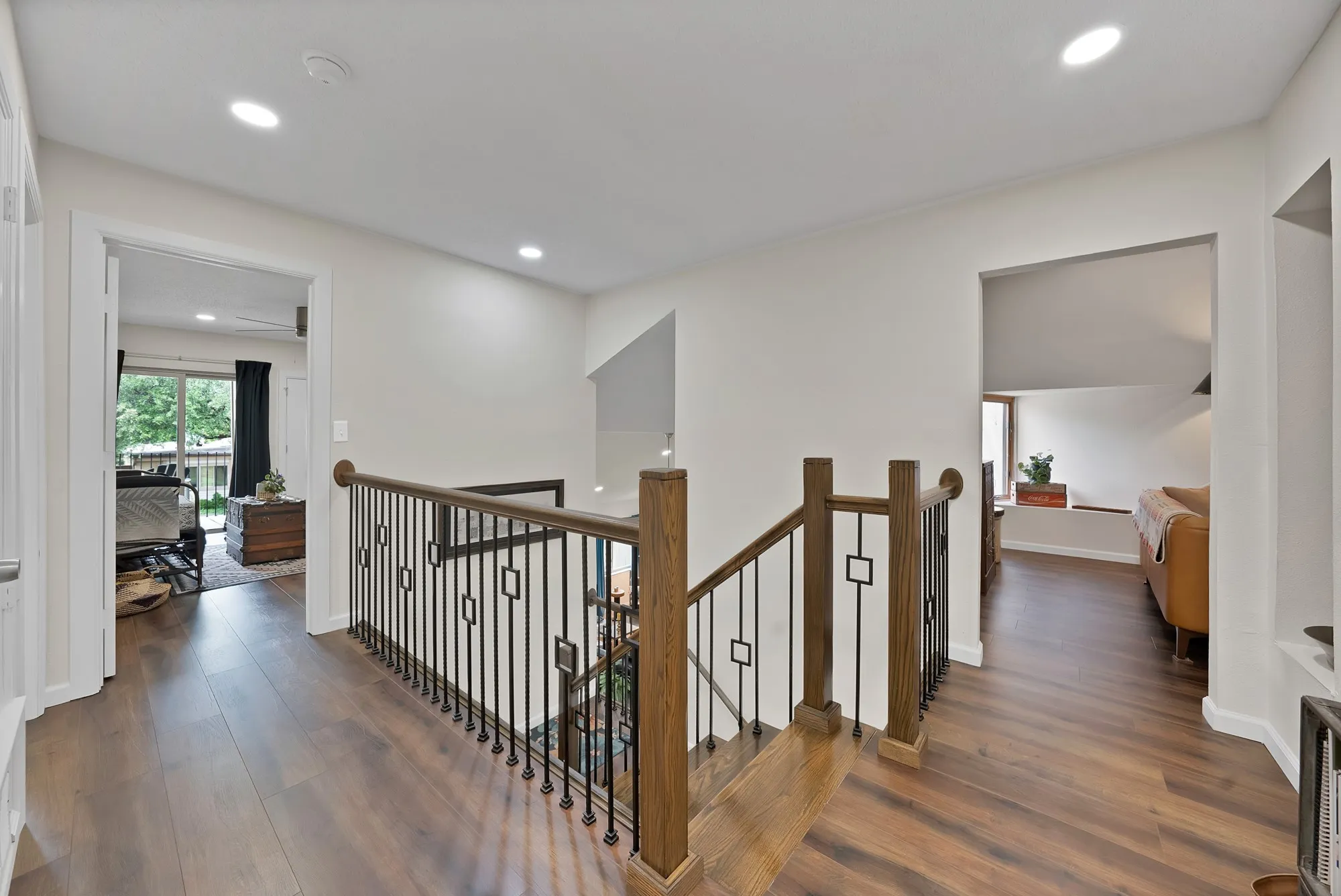 Upstairs landing — Wood flooring landing with iron and wood stair railing, opening to bedroom and living space.v