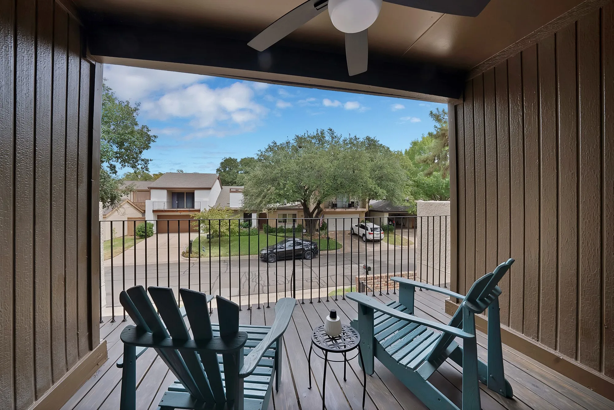 Second floor balcony — Covered balcony with ceiling fan, wrought iron railing, and street view.