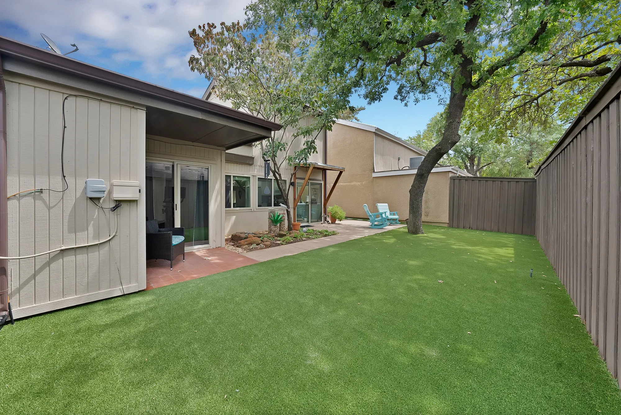 Backyard — Turf lawn with covered patio, sliding glass door, and privacy fencing.