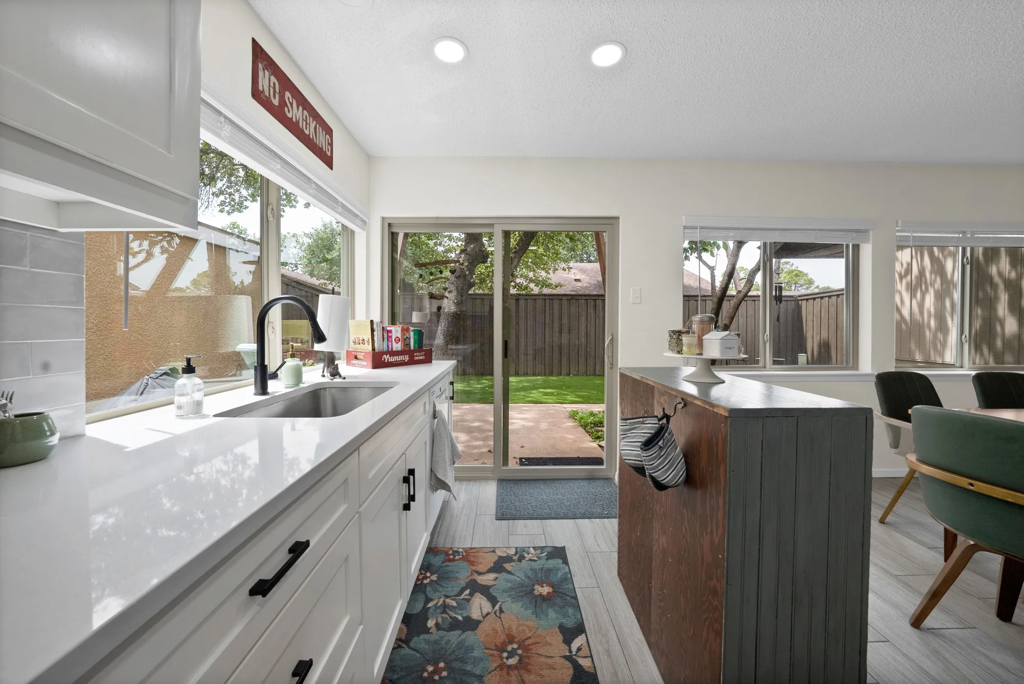Kitchen and dining — Open concept kitchen with sliding glass door to backyard, blue painted kitchen island, and view into dining area with built-in hutch.