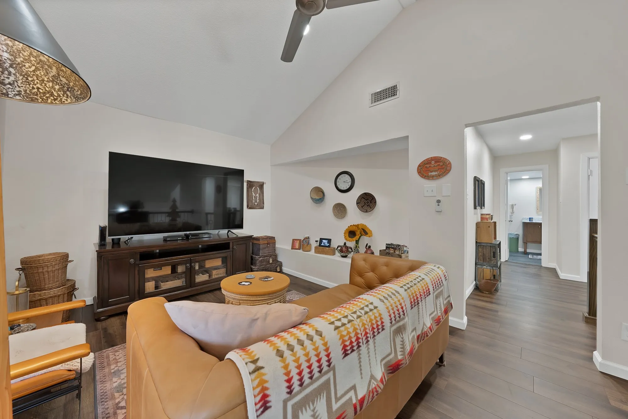 Upstairs loft living area — Vaulted beam ceiling with ceiling fan, large window, and open sightline to stair railing below.