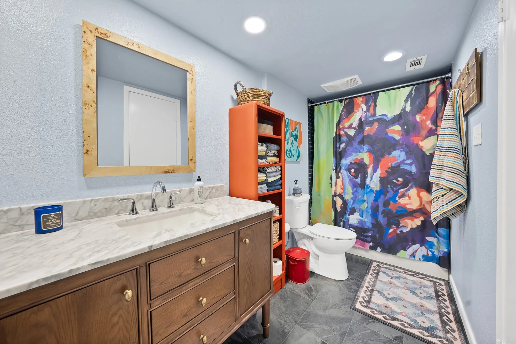 Bathroom — Marble style vanity countertop with wood cabinetry, gold hardware, and tile flooring. Tub and shower combo with tiled surround.