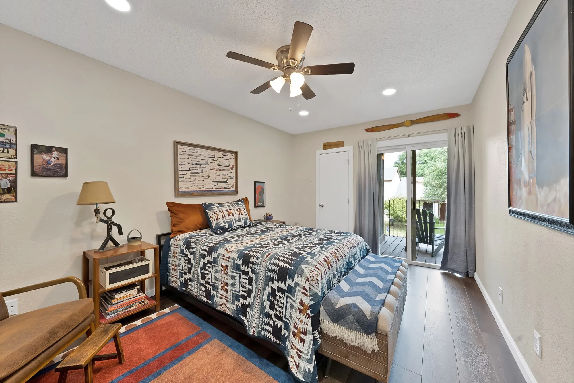 Bedroom — Wood look flooring with sliding glass door to balcony, ceiling fan, and closet.