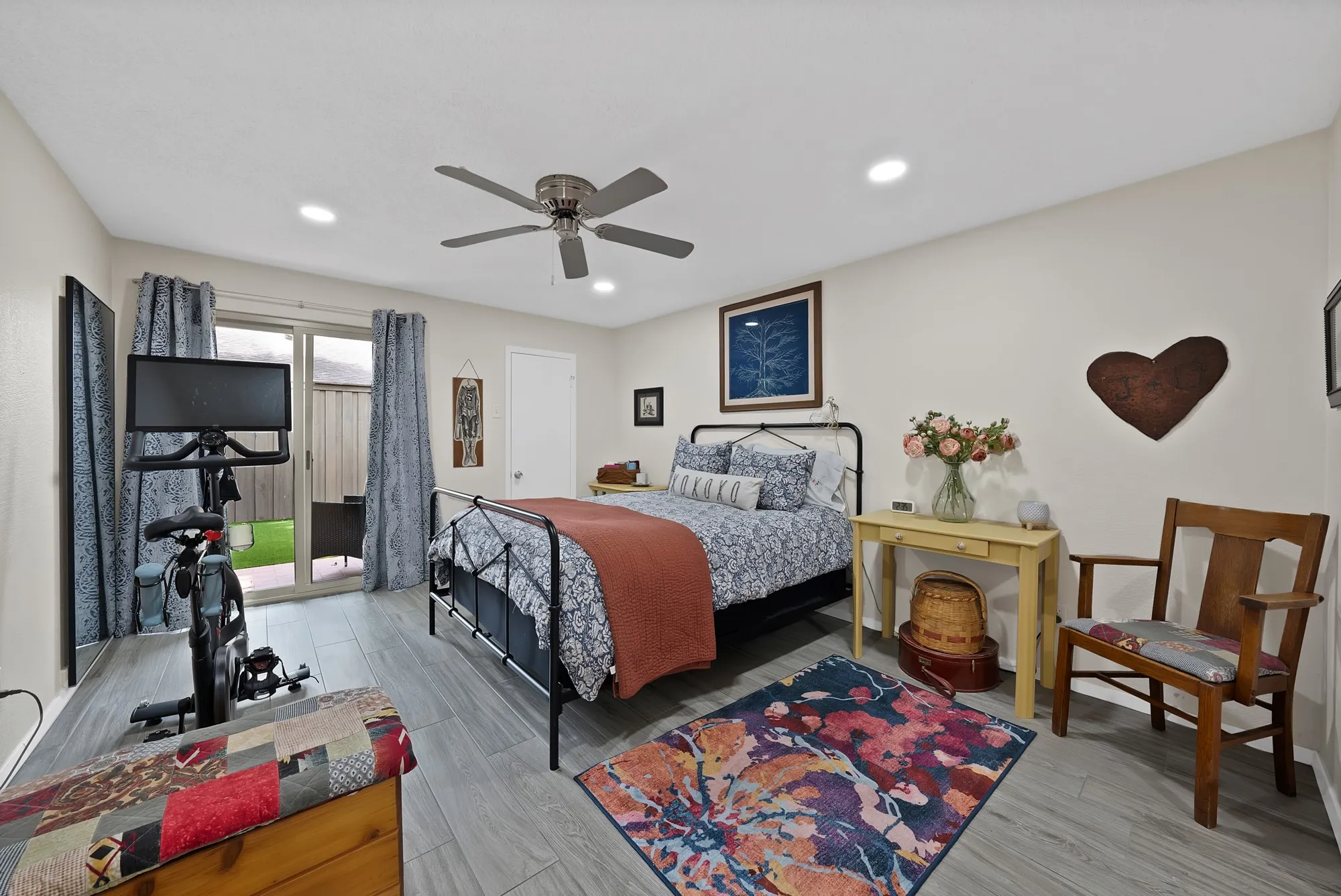 Primary bedroom — Wood look tile flooring with sliding glass door to backyard patio and ceiling fan.