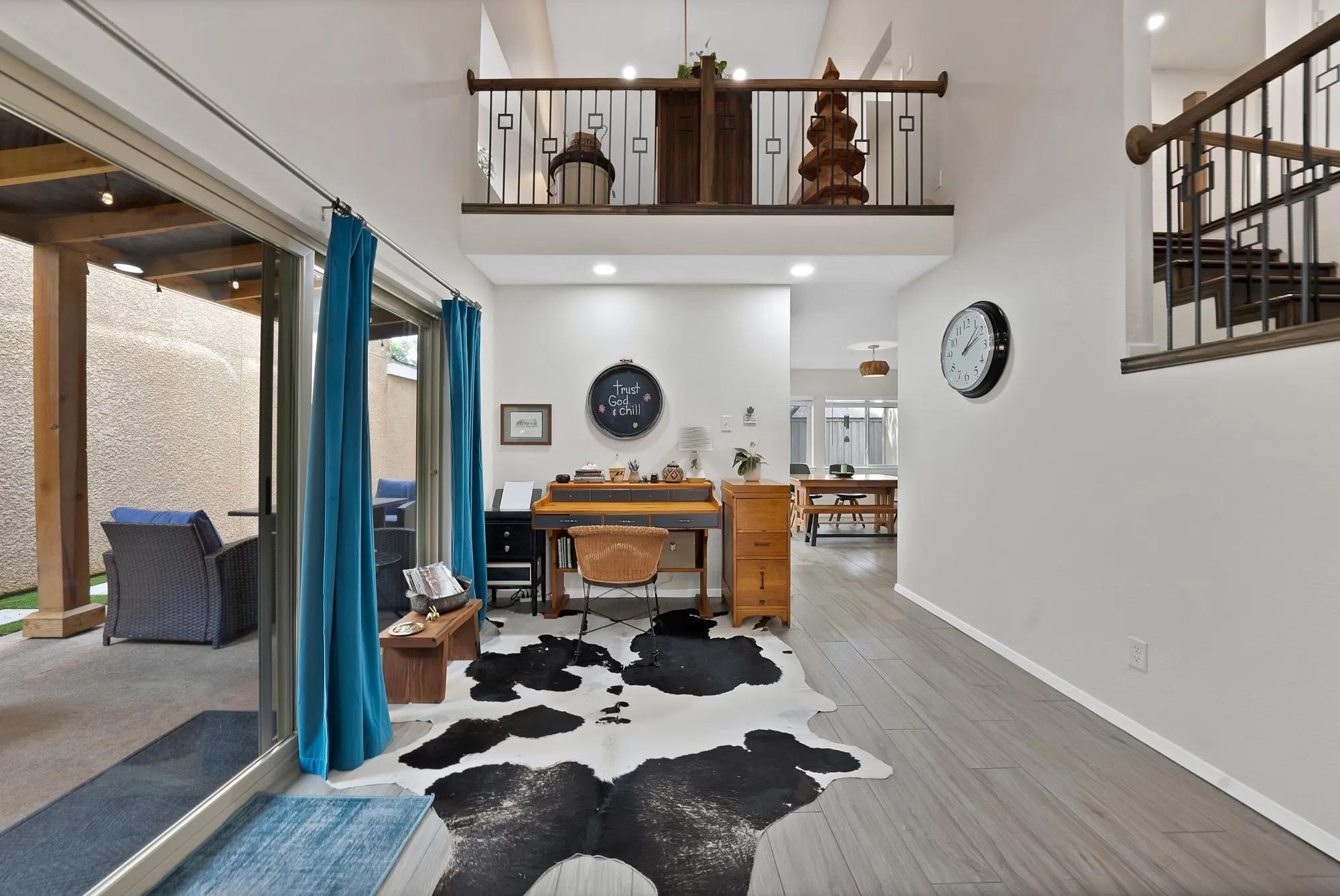 Entry and loft overlook — Two story entry with iron railing loft overlook, wood staircase with iron balusters, and wood look tile flooring.