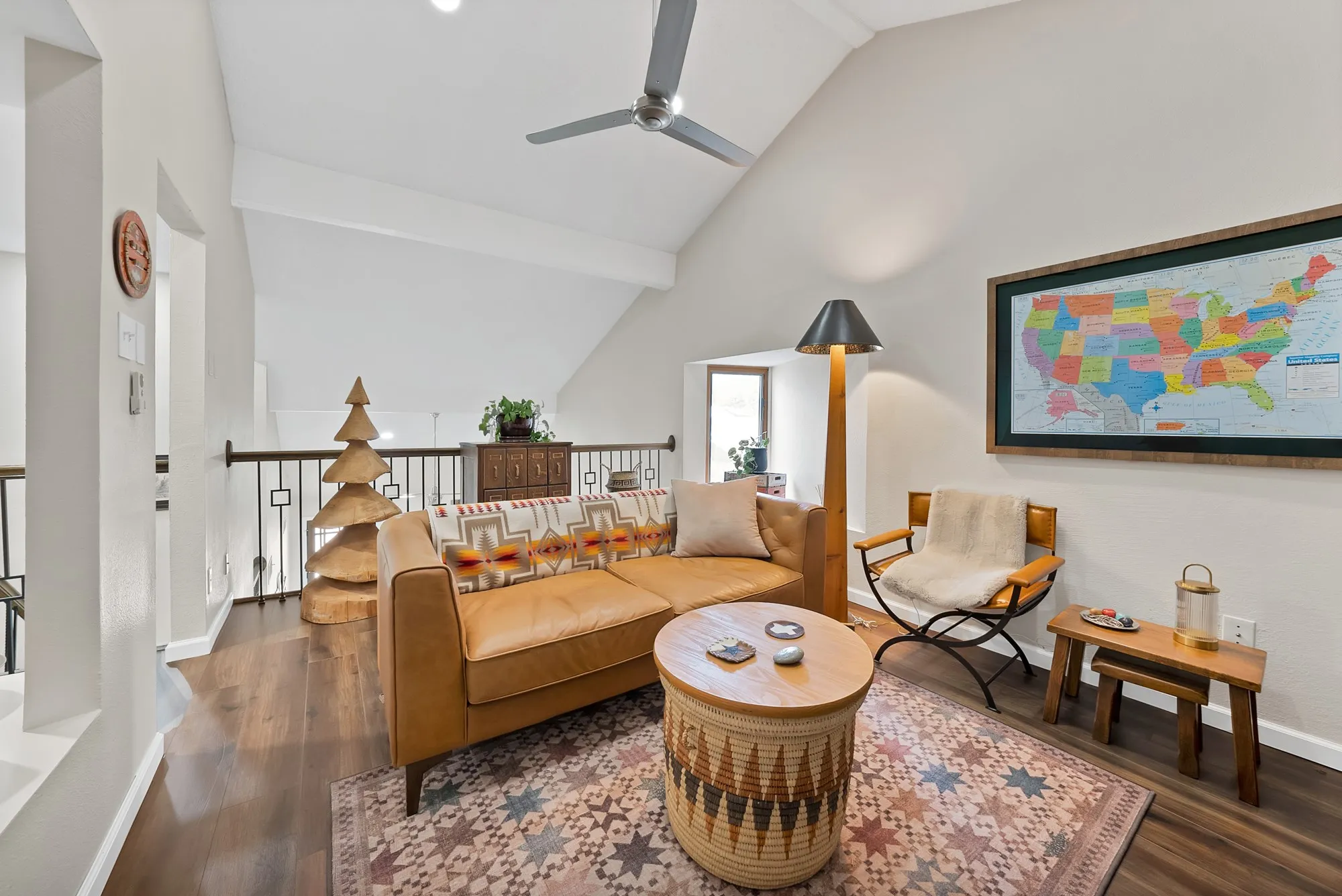 Upstairs loft living area — Vaulted ceiling seating area with ceiling fan and large window overlooking the stairwell.