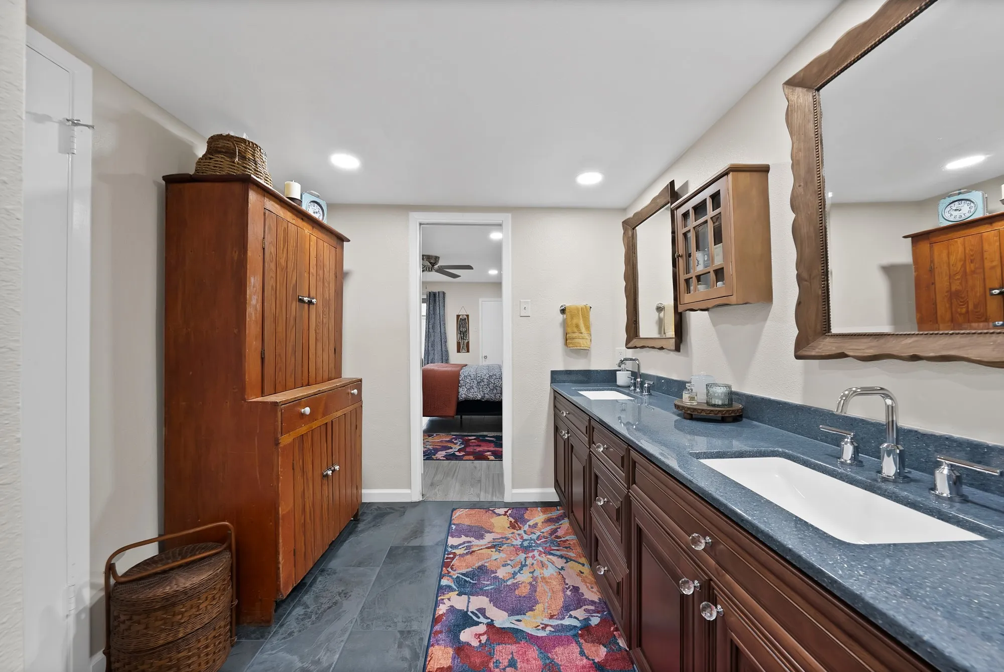 Primary bathroom — Dual vanity with gray solid surface countertop, dark wood cabinetry, and marble tile tub and shower surround.