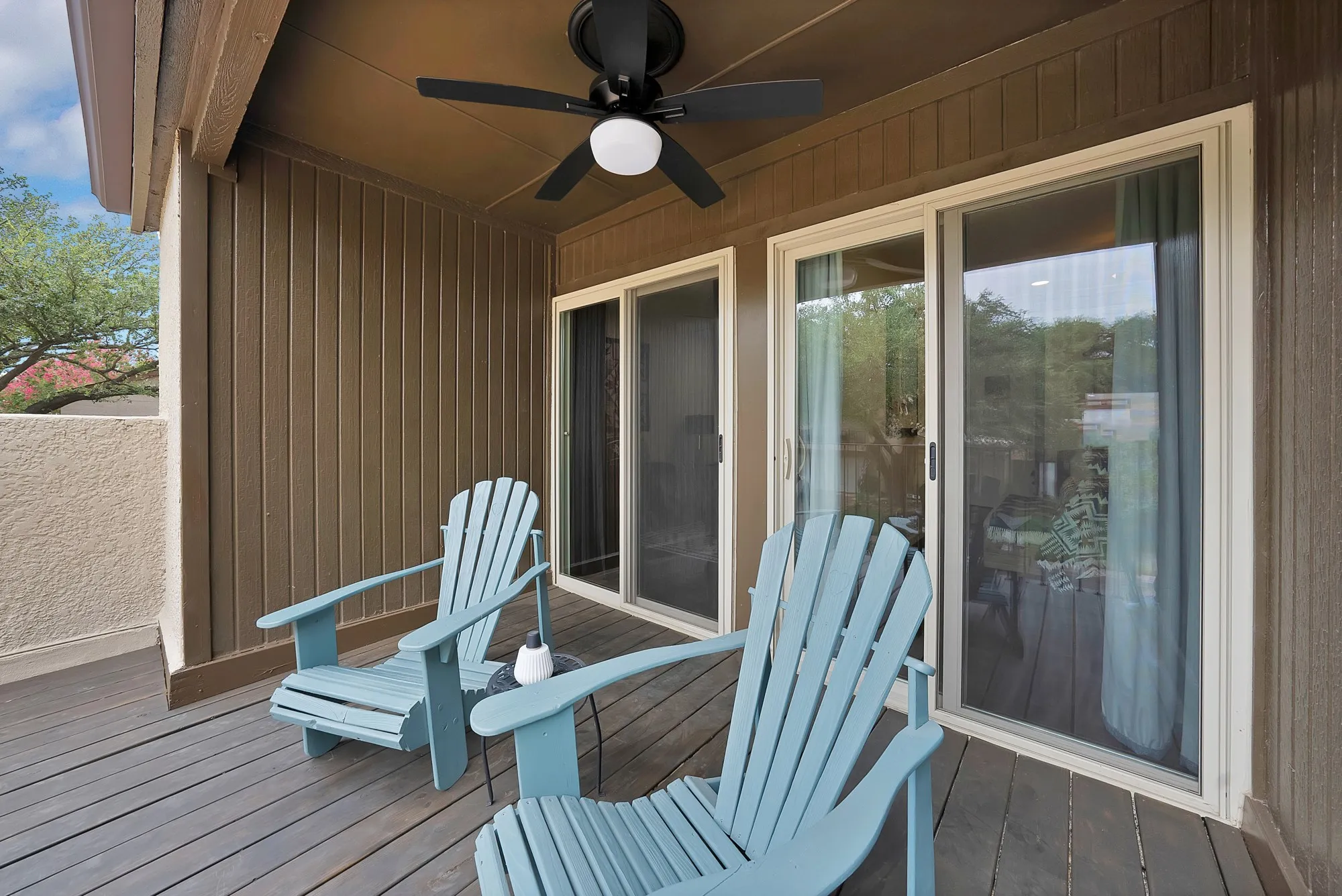 Second floor balcony — Covered balcony with ceiling fan, two sliding glass doors, and pastel blue Adirondack chairs.