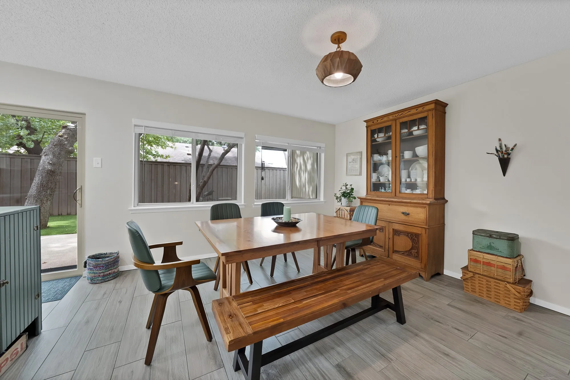 Dining room — Dining space with sliding glass door to backyard, built-in china cabinet, and wood look tile flooring.