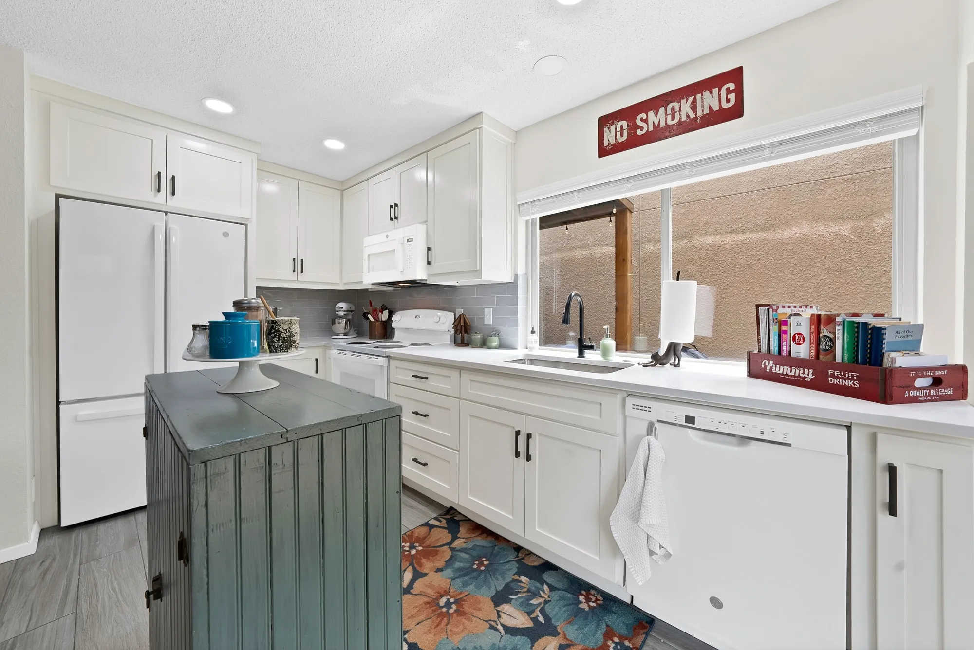 Kitchen — White shaker cabinetry, quartz countertops, gray subway tile backsplash, and stainless refrigerator. Center island with additional storage.