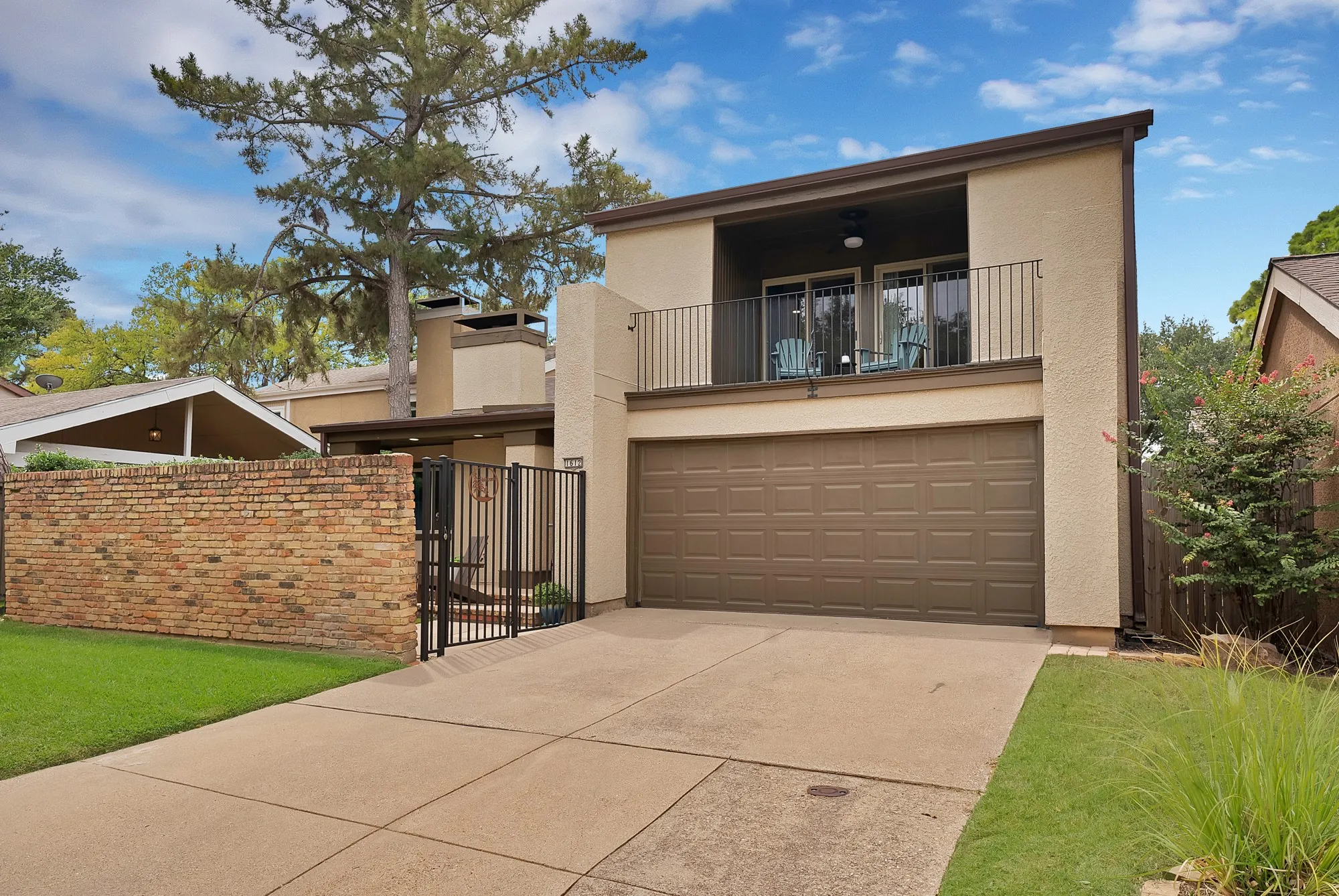 Front exterior — Side angle view of stucco and brick facade with vaulted roofline, chimney, and second floor balcony.