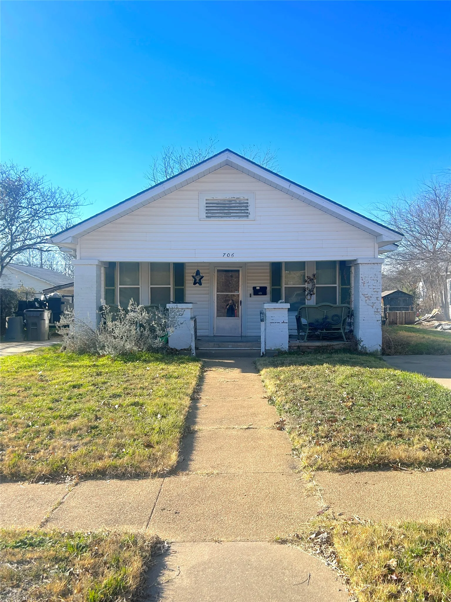 Gabled roofline, front porch, concrete walkway, and established lawn area
