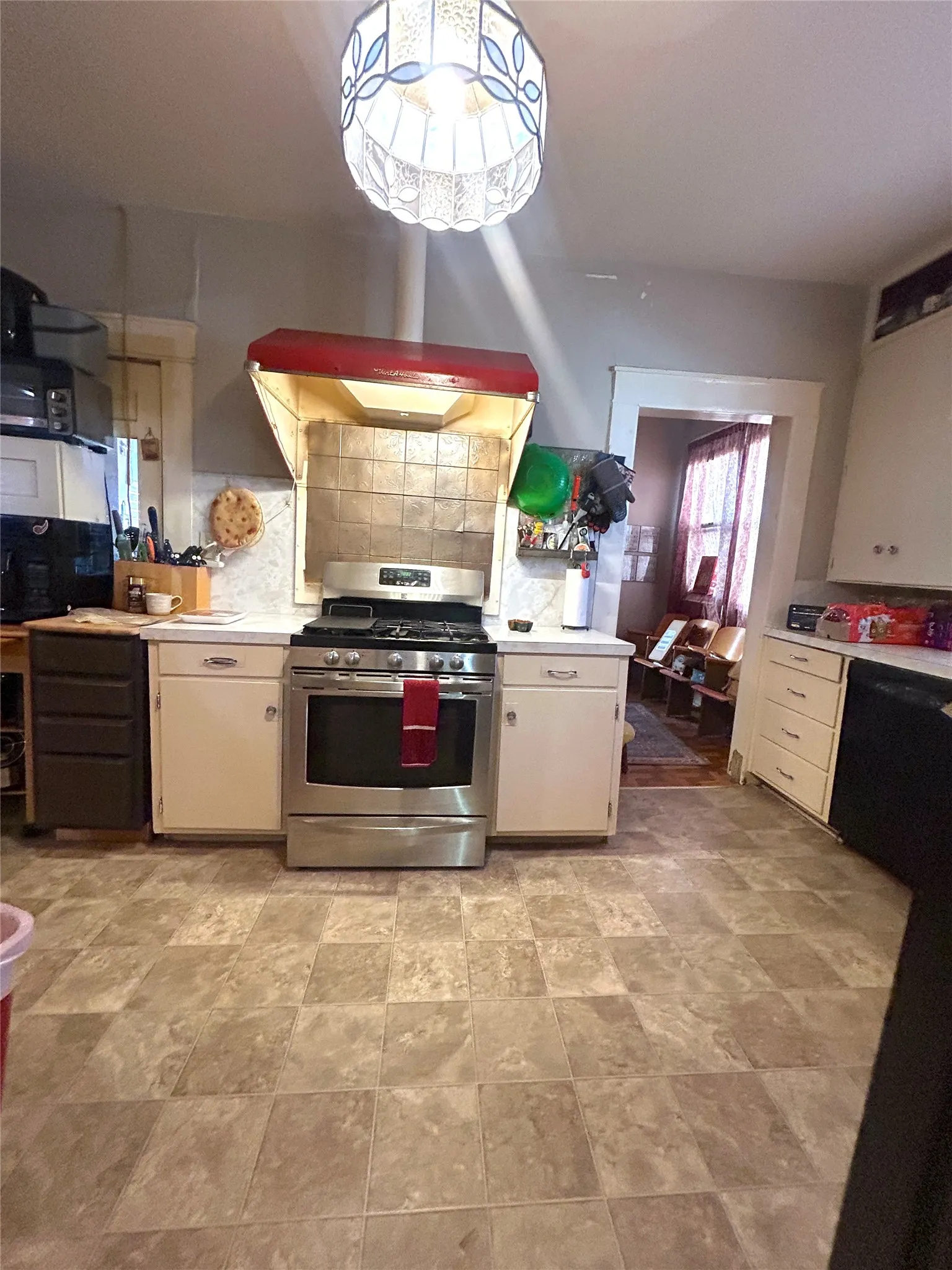 Stainless steel range with a tile backsplash and red range hood
