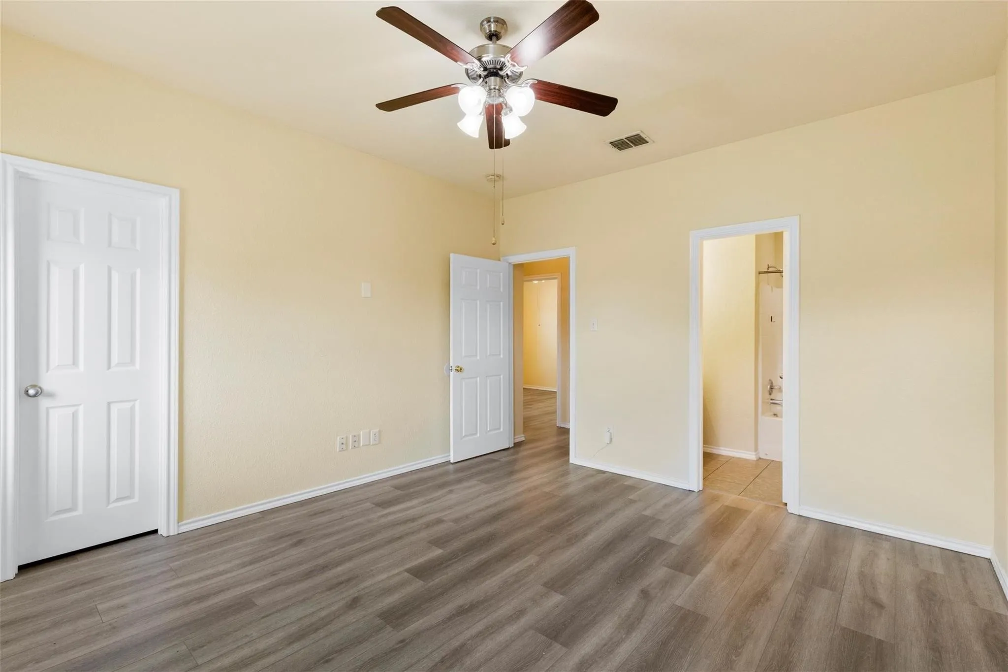 Wood-finish flooring with a ceiling fan and light fixture