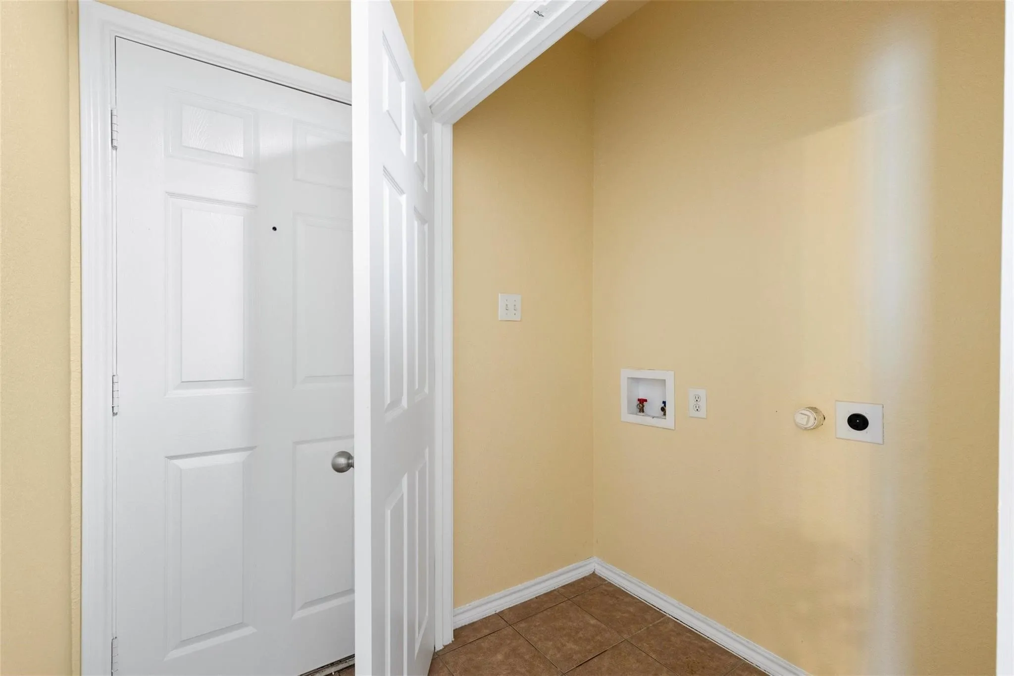 Utility area with light-toned walls and durable tile flooring